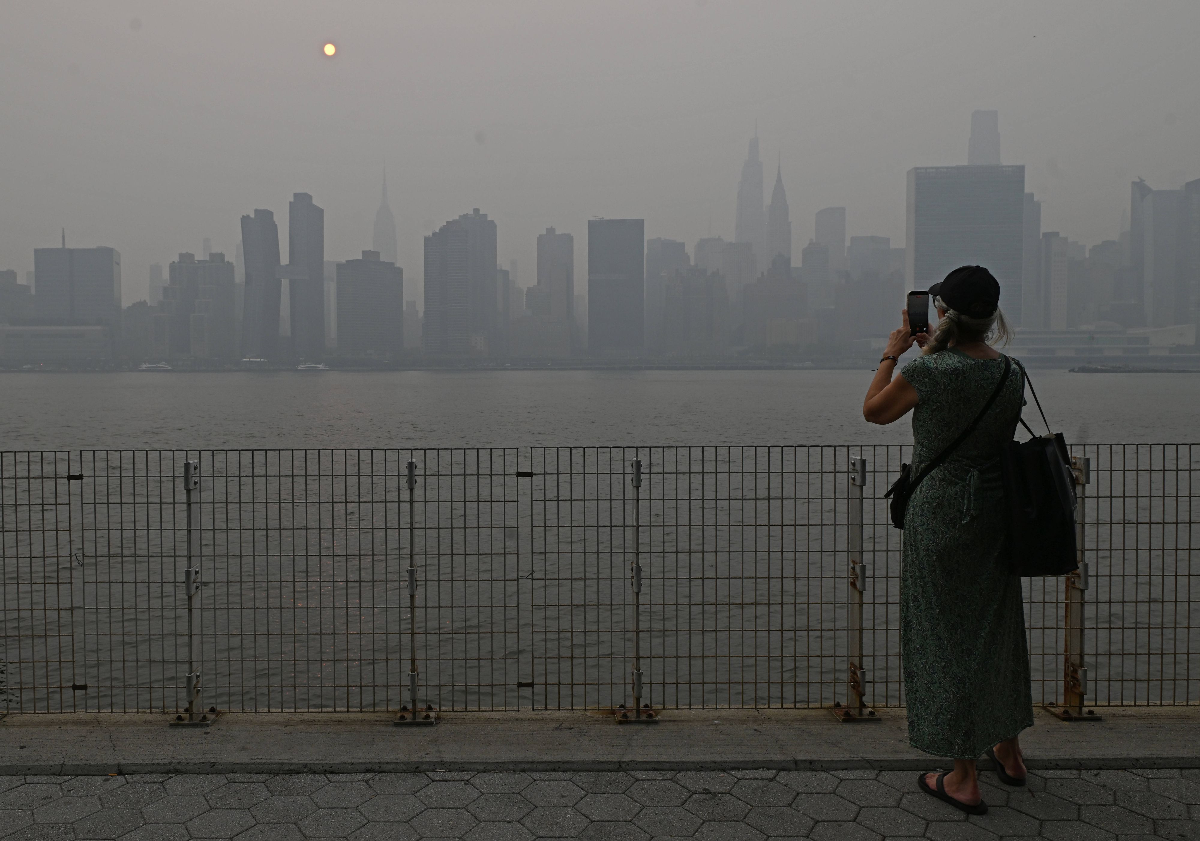 Eine Touristin fotografiert die Skyline von Manhattan, die Sicht ist schlecht.