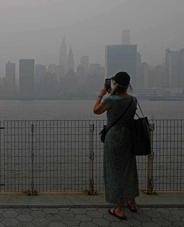 Eine Touristin fotografiert die Skyline von Manhattan, die Sicht ist schlecht.