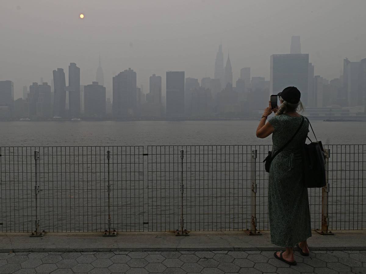 Eine Touristin fotografiert die Skyline von Manhattan, die Sicht ist schlecht.