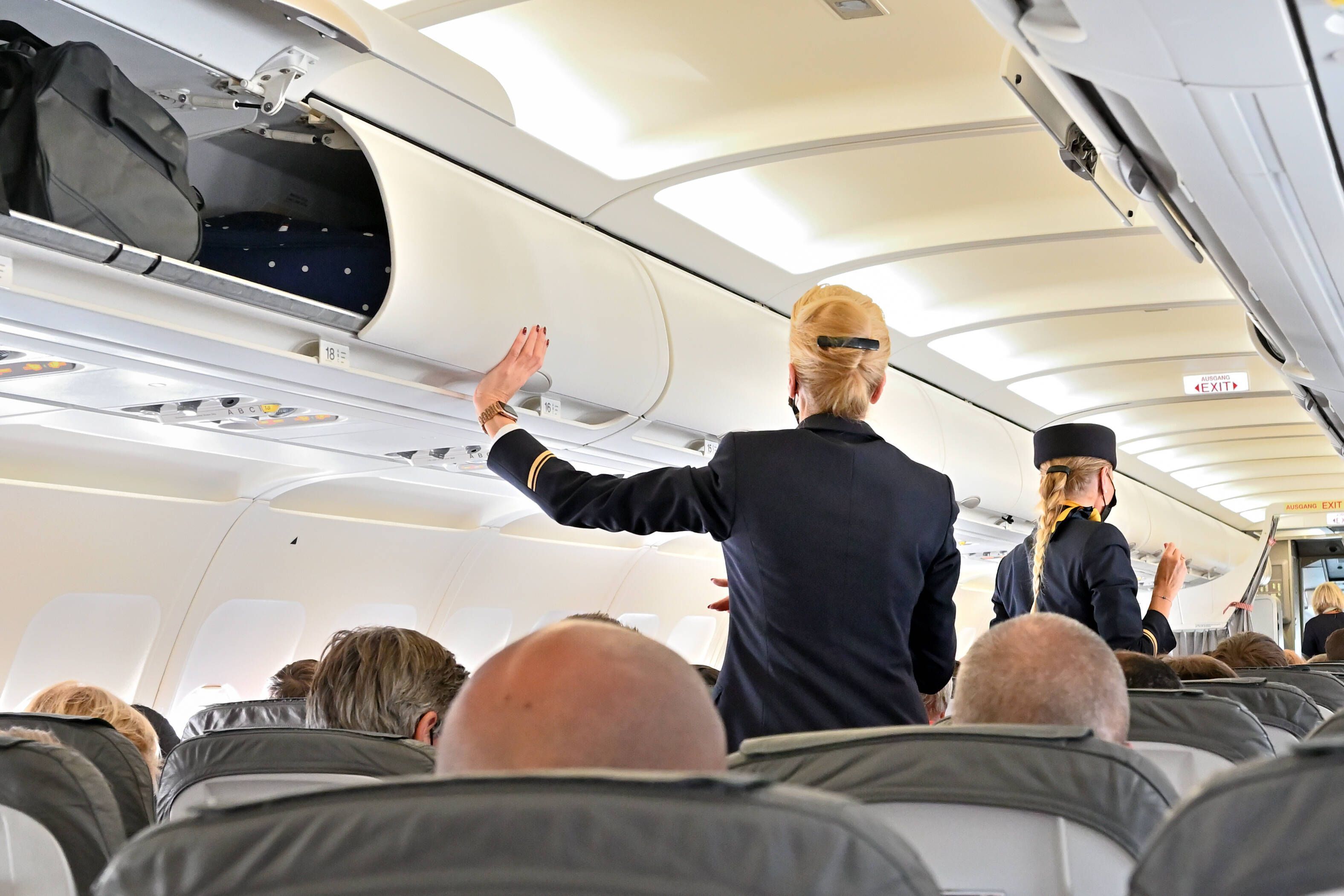 Eine Stewardess schließt die Handgepäckfächer vor dem Abflug. (Symbolfoto)