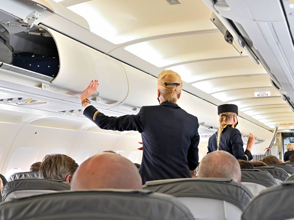 Eine Stewardess schließt die Handgepäckfächer vor dem Abflug. (Symbolfoto)