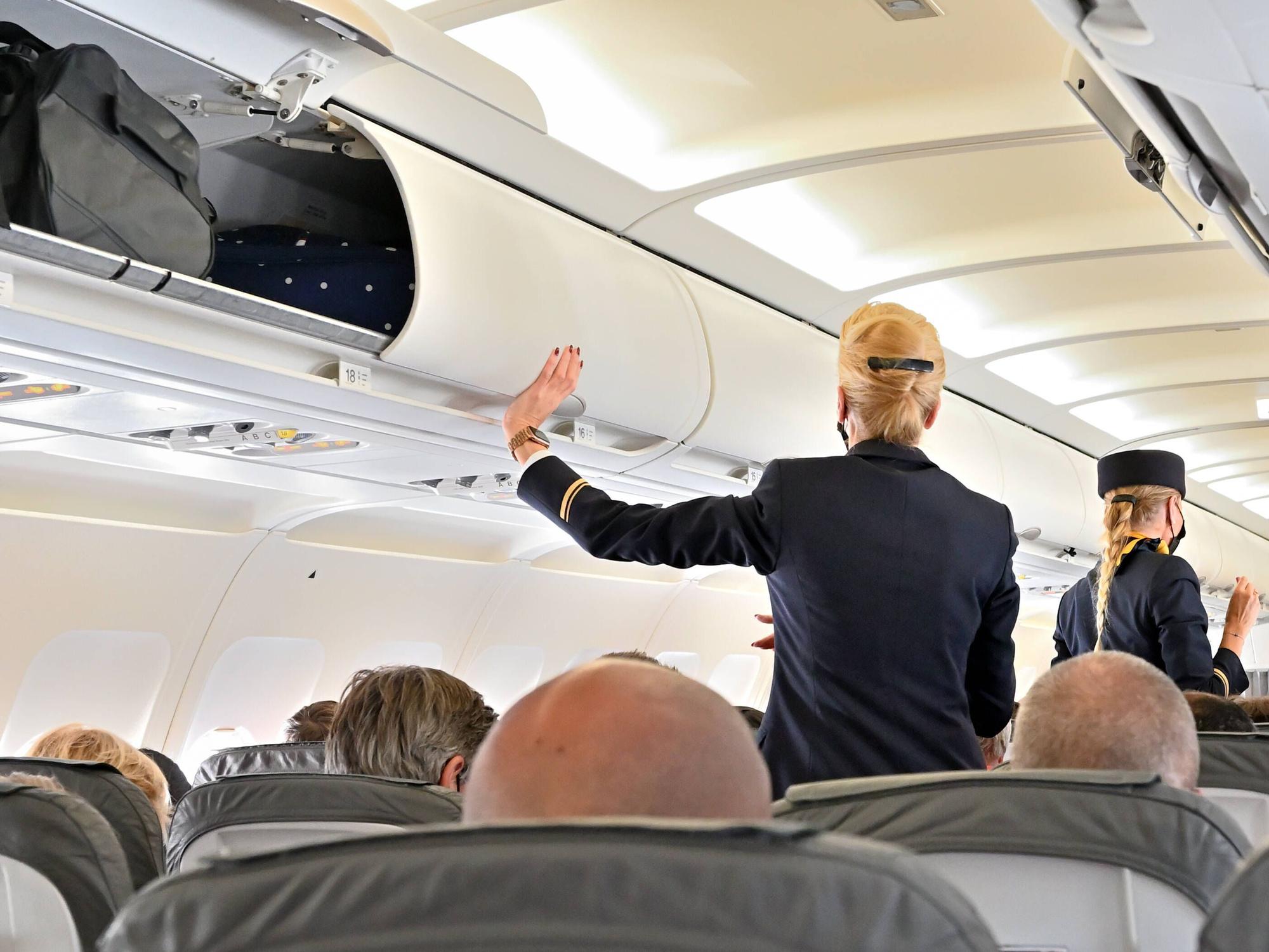 Eine Stewardess schließt die Handgepäckfächer vor dem Abflug. (Symbolfoto)