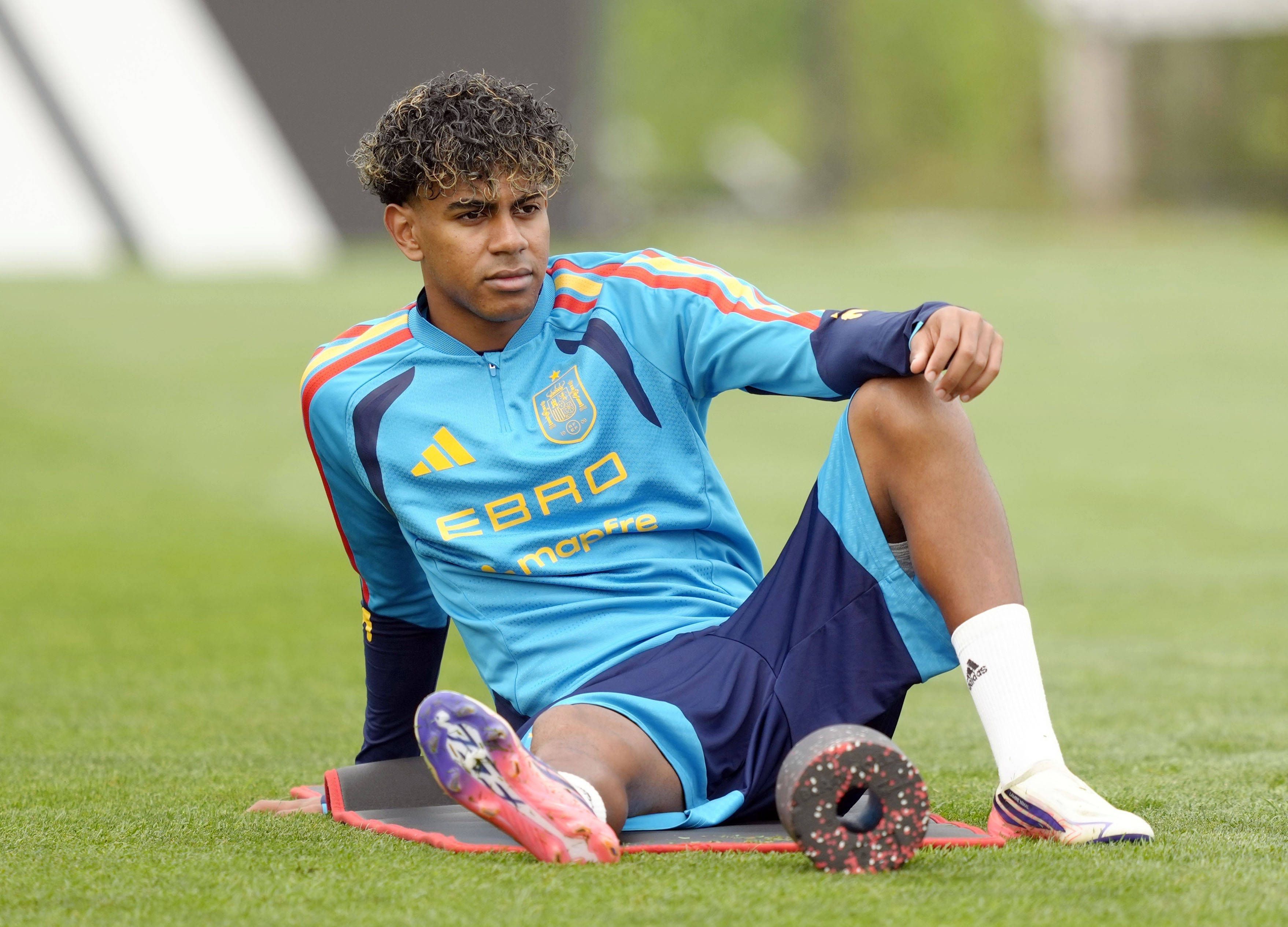 Lamine Yamal sitzt beim Training auf einer Matte und dehnt sich.