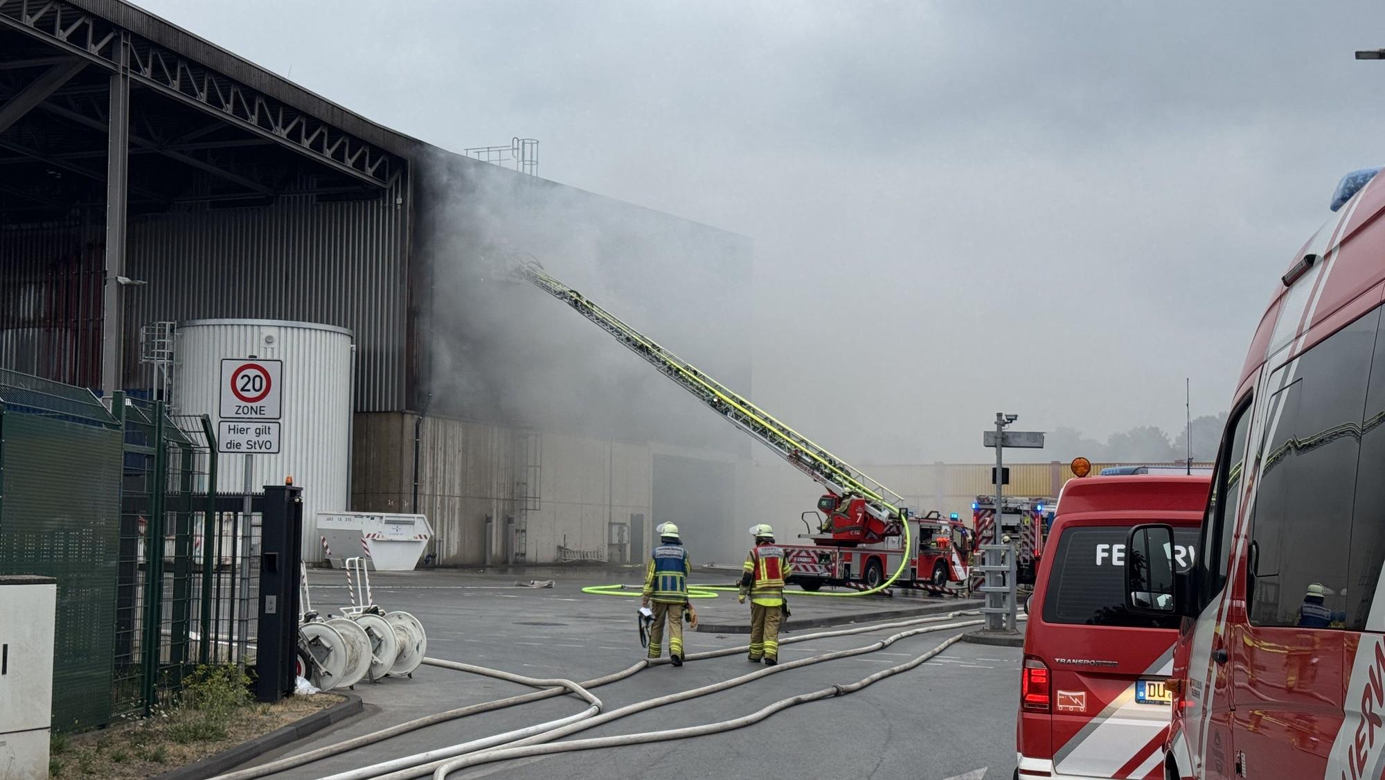 Feuerwehrleute löschen einen Brand auf einem Recyclinghof in Duisburg.