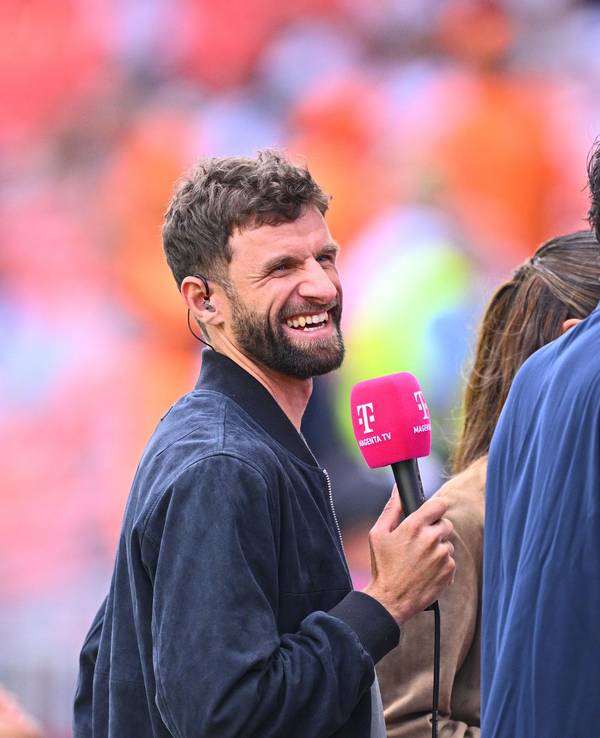 Thomas Müller und Mats Hummels lachen mit MagentaTV-Mikros in der Hand.