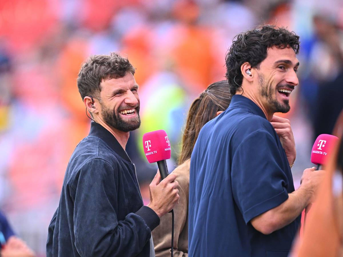 Thomas Müller und Mats Hummels lachen mit MagentaTV-Mikros in der Hand.
