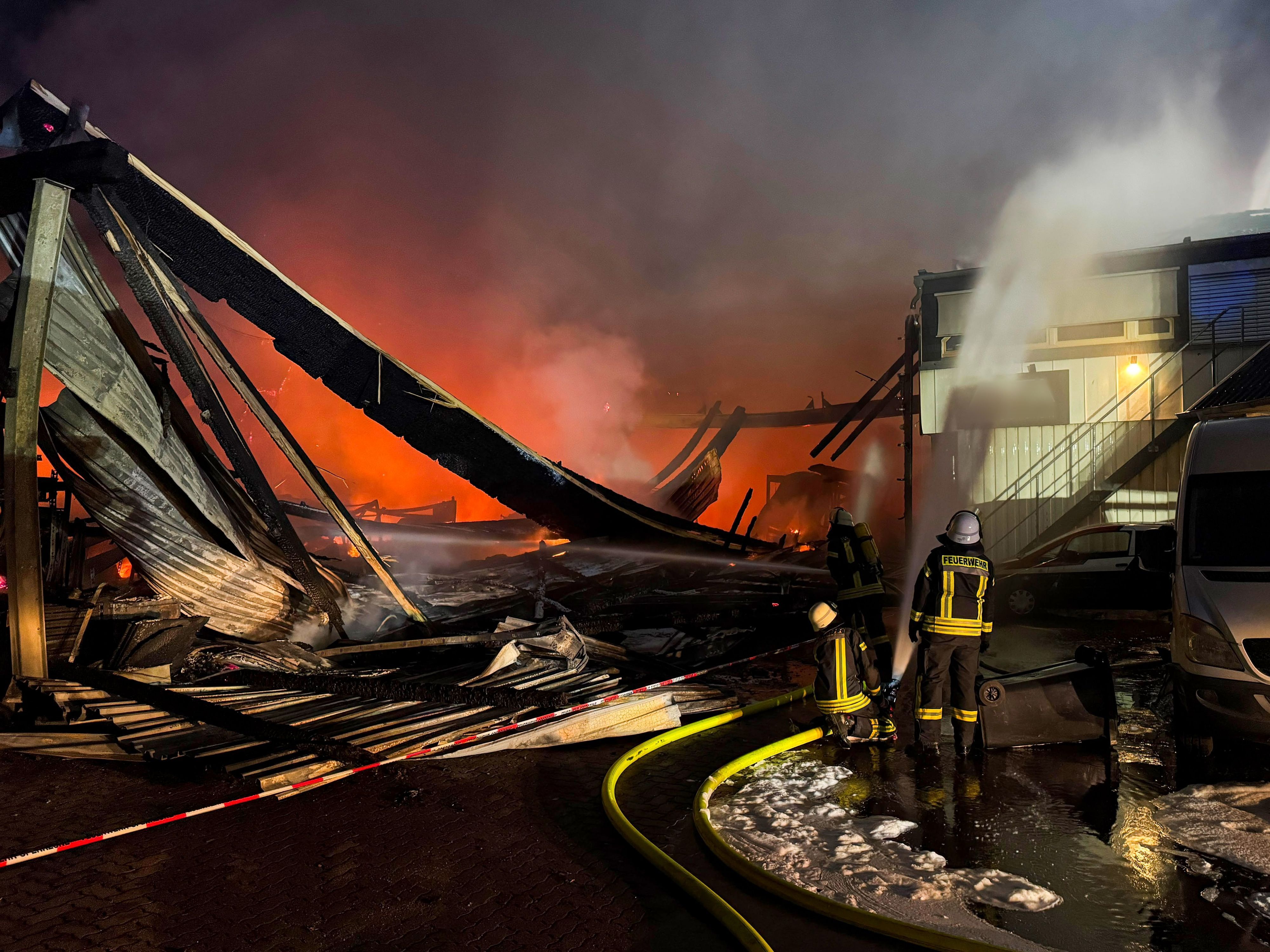 Feuerwehrleute sind mit Löscharbeiten bei einem Brand in einer Industriehalle in Wassenberg beschäftigt.