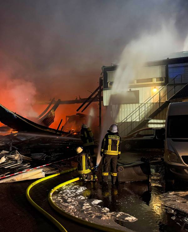Feuerwehrleute sind mit Löscharbeiten bei einem Brand in einer Industriehalle in Wassenberg beschäftigt.