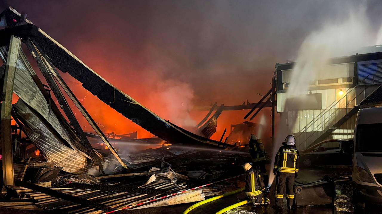 Feuerwehrleute sind mit Löscharbeiten bei einem Brand in einer Industriehalle in Wassenberg beschäftigt.