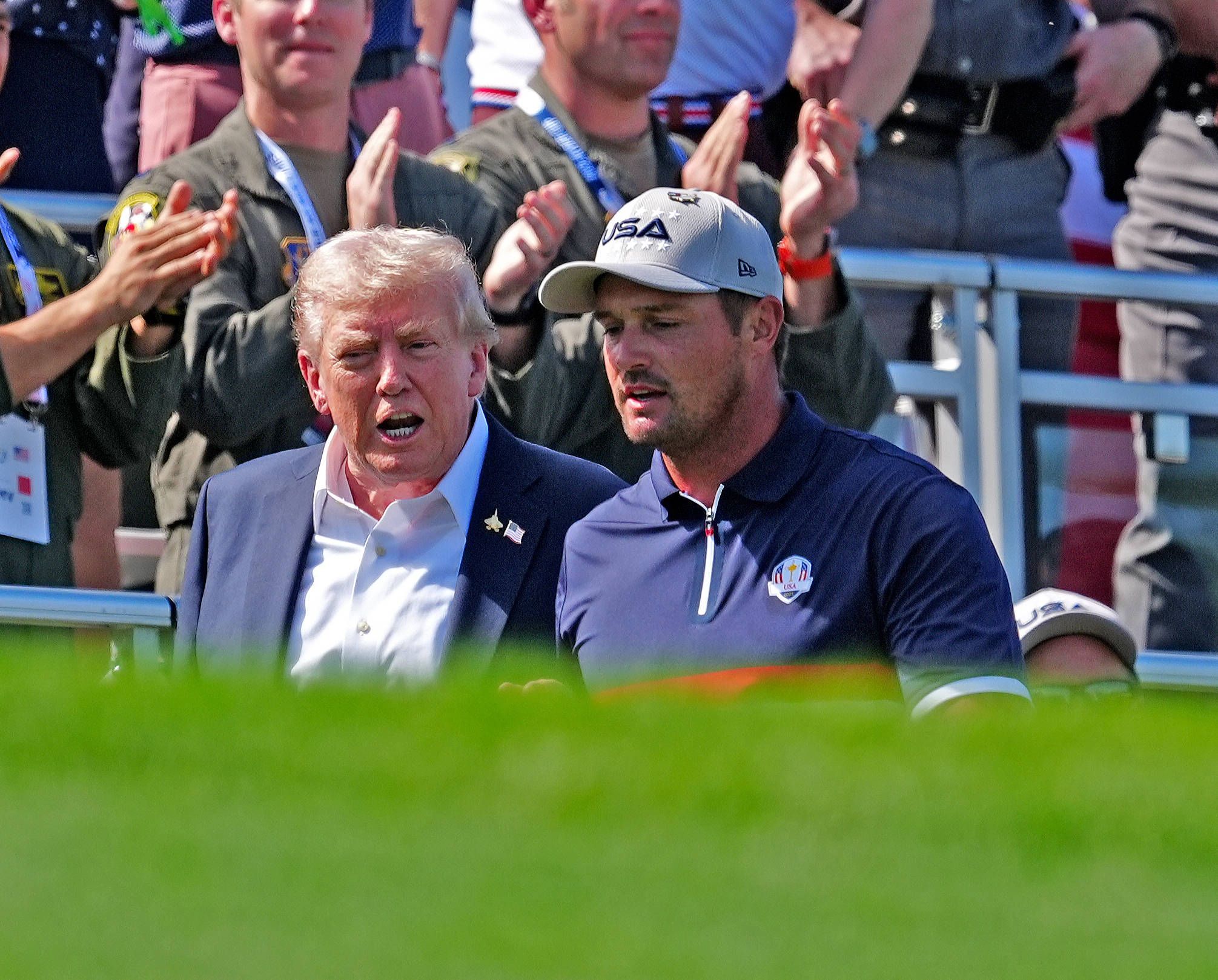 Donald Trump und Bryson DeChambeau gehen zusammen über einen Golf-Platz.