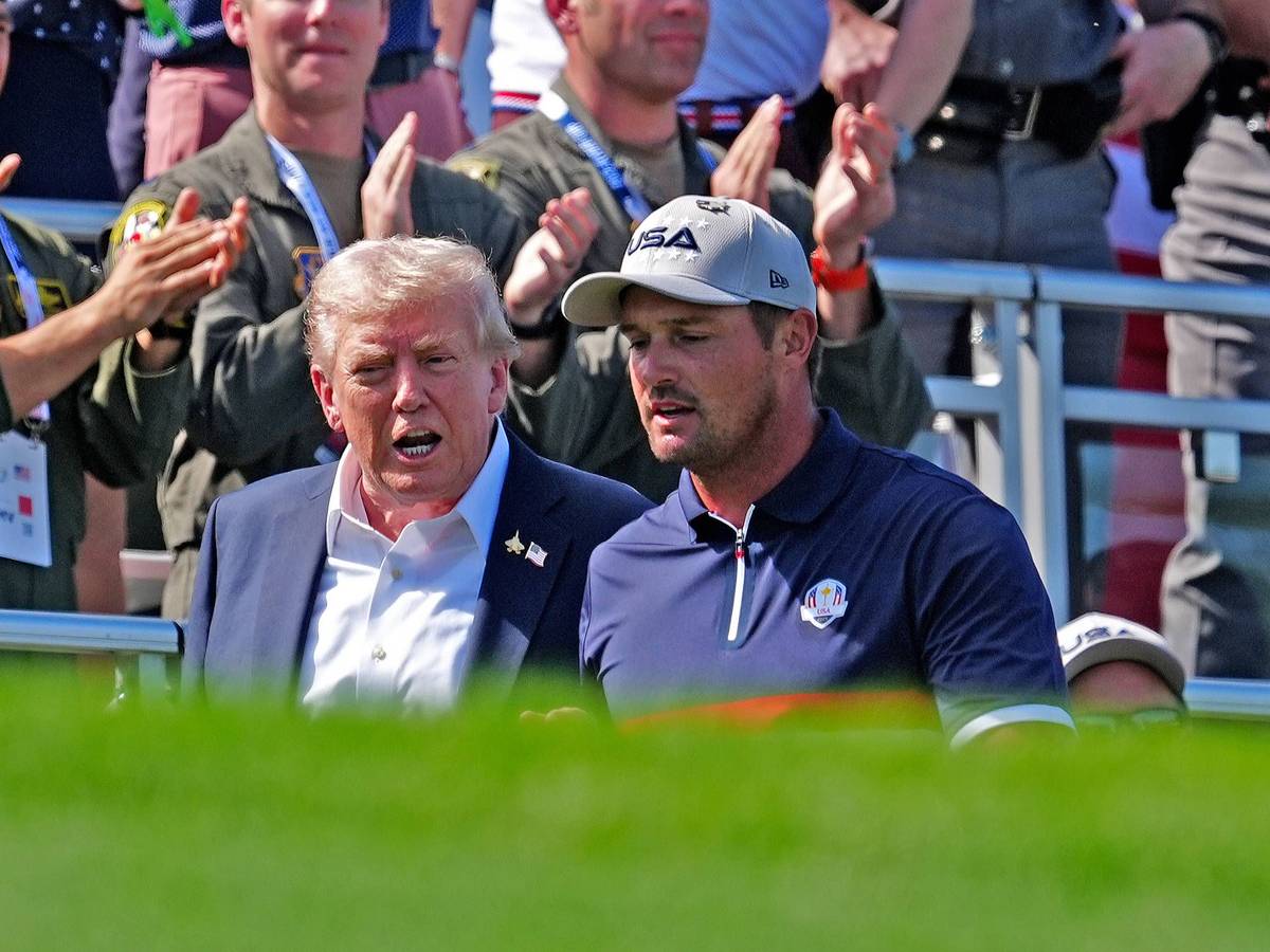 Donald Trump und Bryson DeChambeau gehen zusammen über einen Golf-Platz.