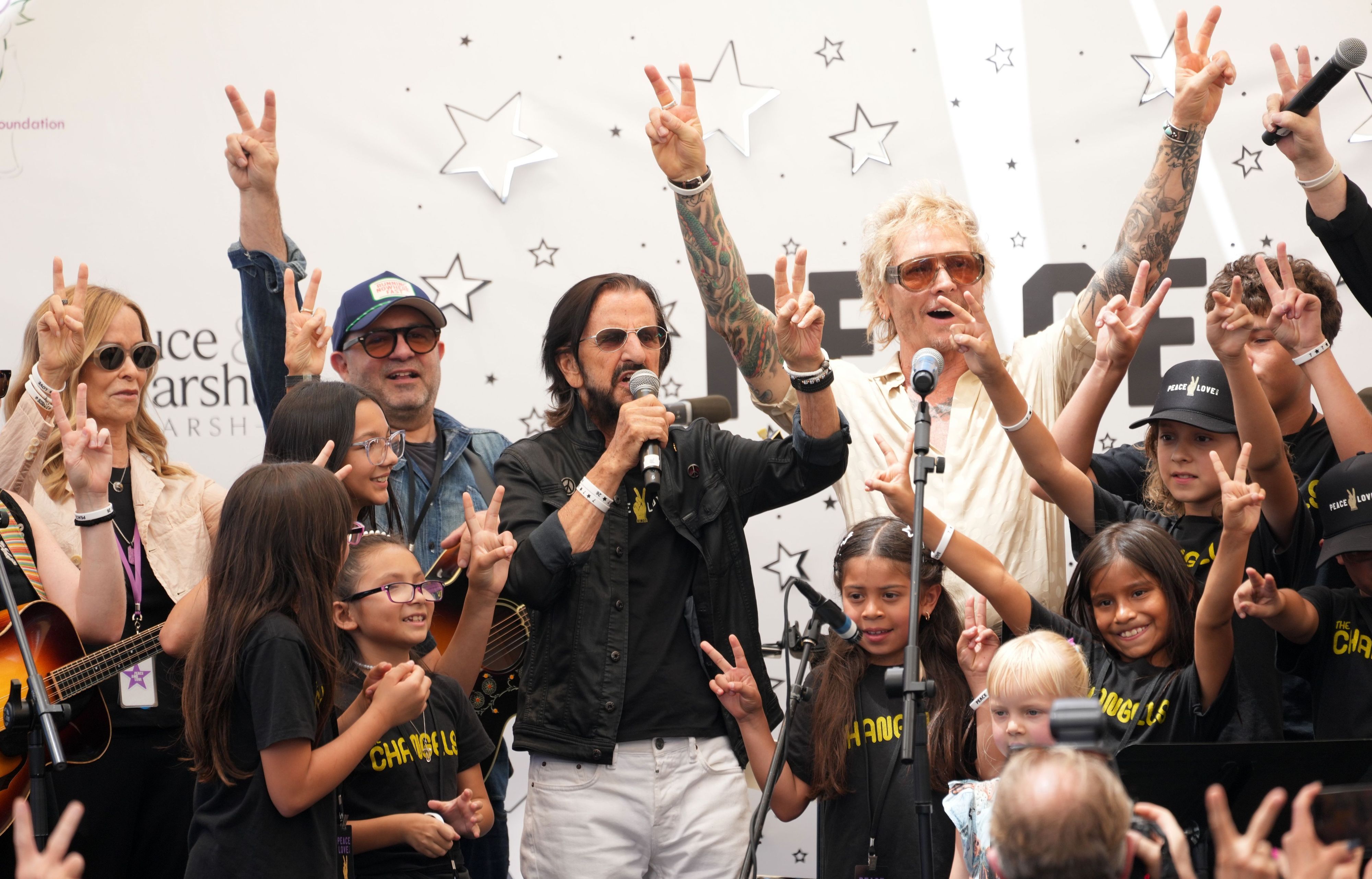 Ringo Starr (M) spricht zu den Zuschauern, während Freunde, Kinder und Musiker zu ihm auf die Bühne kommen – anlässlich der jährlichen „Peace & Love“-Feier zu seinem 86. Geburtstag.