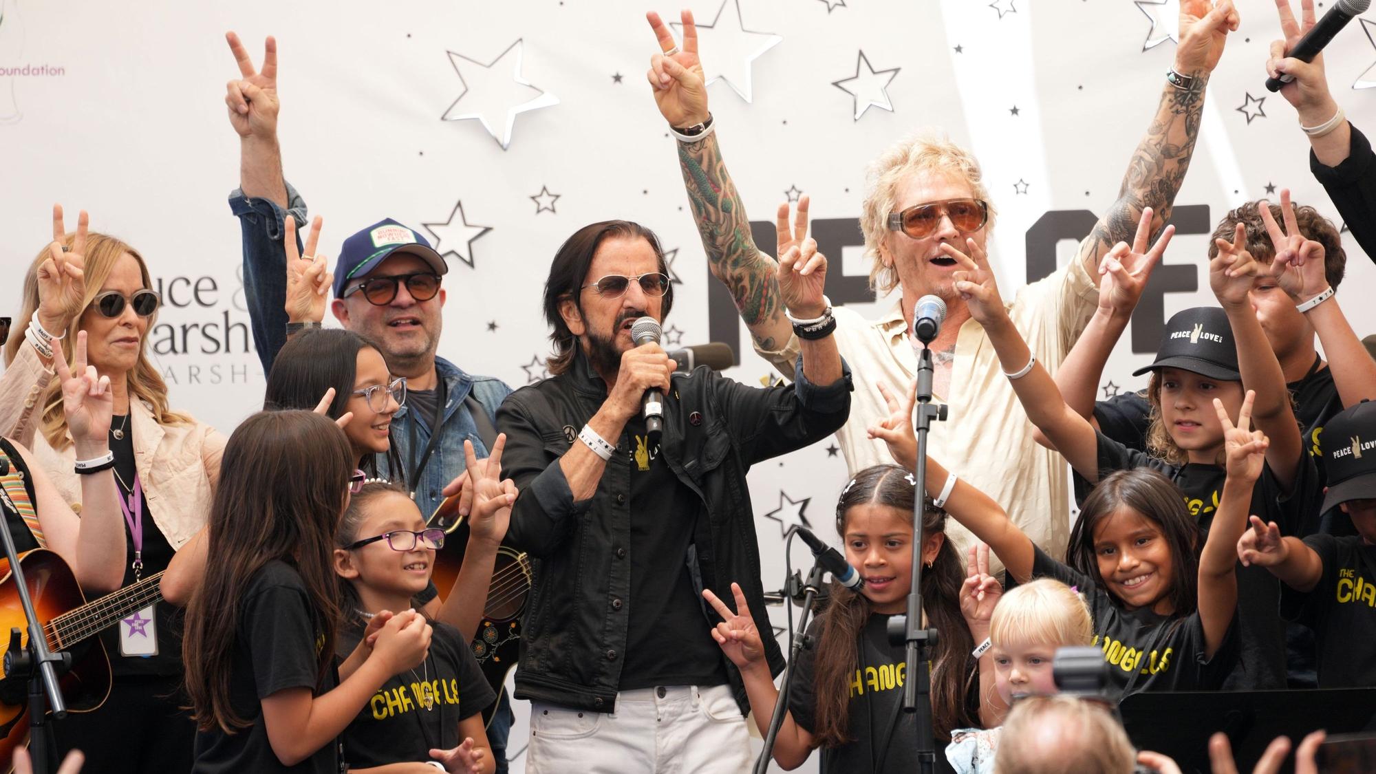 Ringo Starr (M) spricht zu den Zuschauern, während Freunde, Kinder und Musiker zu ihm auf die Bühne kommen – anlässlich der jährlichen „Peace & Love“-Feier zu seinem 86. Geburtstag.