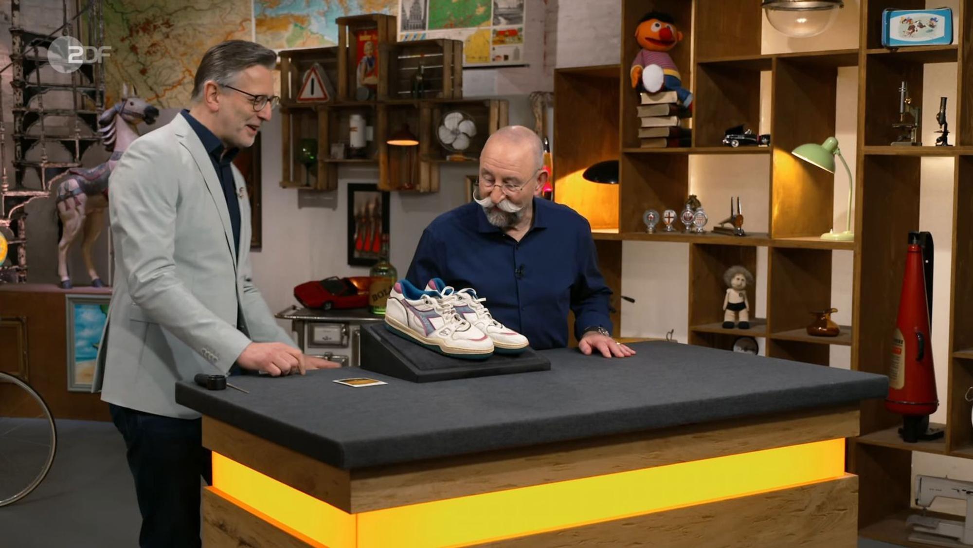 „Detlev, du kannst doch nicht deine Turnschuhe auf den Tisch stellen!“, mahnte Horst Lichter (rechts) in der Dienstagsausgabe von „Bares für Rares“ im Scherz. (Bild: ZDF)