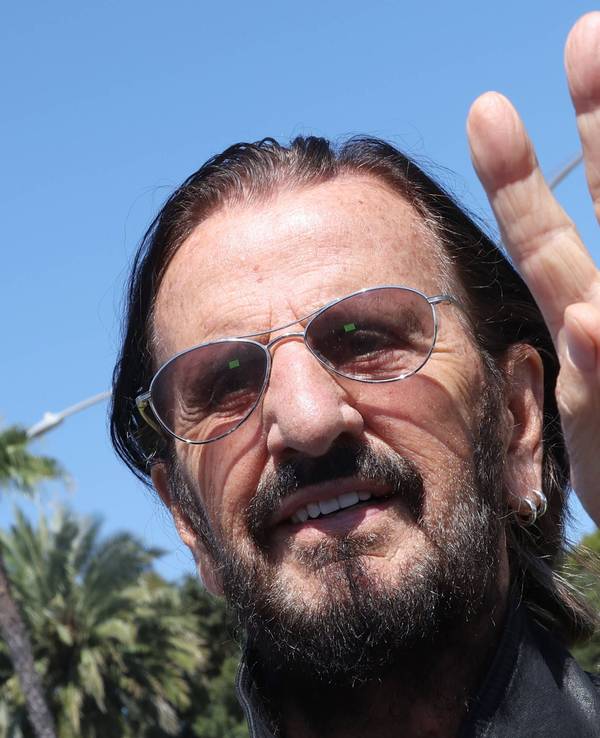 Ringo Starr macht ein Peace-Zeichen.