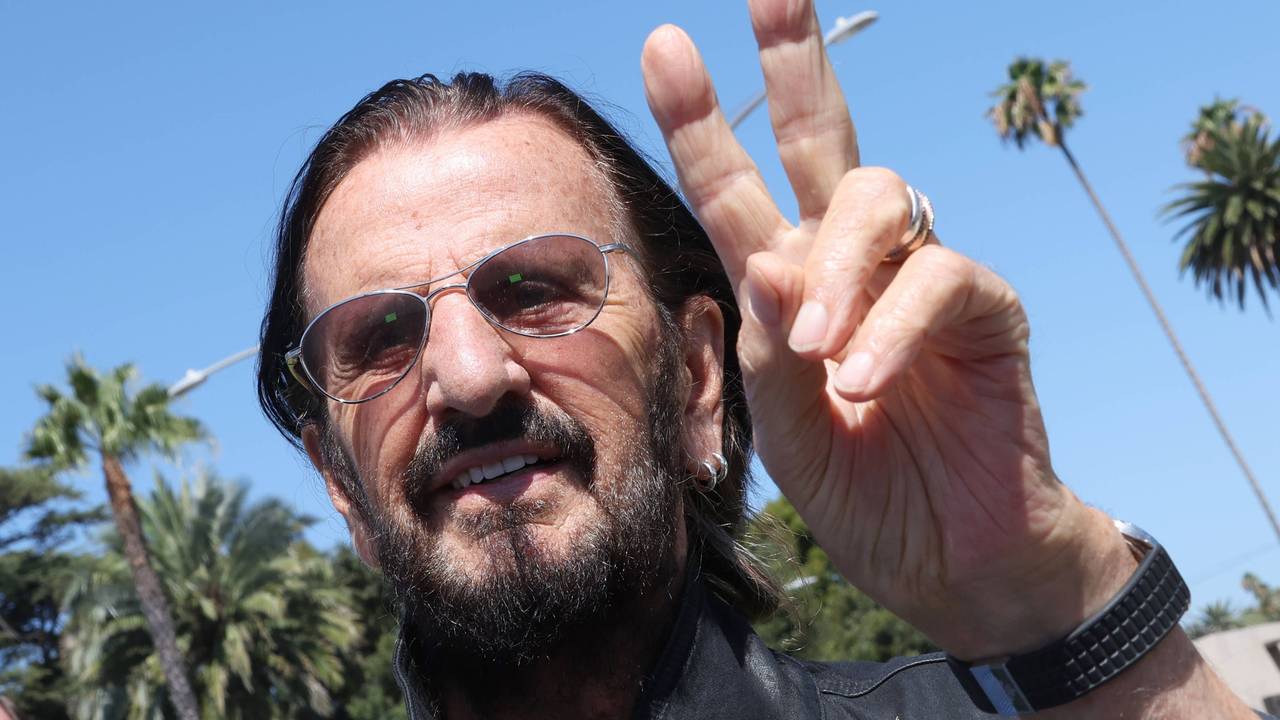 Ringo Starr macht ein Peace-Zeichen.
