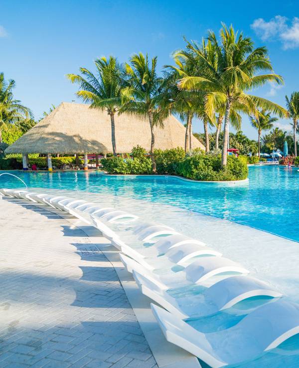 Swimming Pool mit viel Sonne und Palmen.
