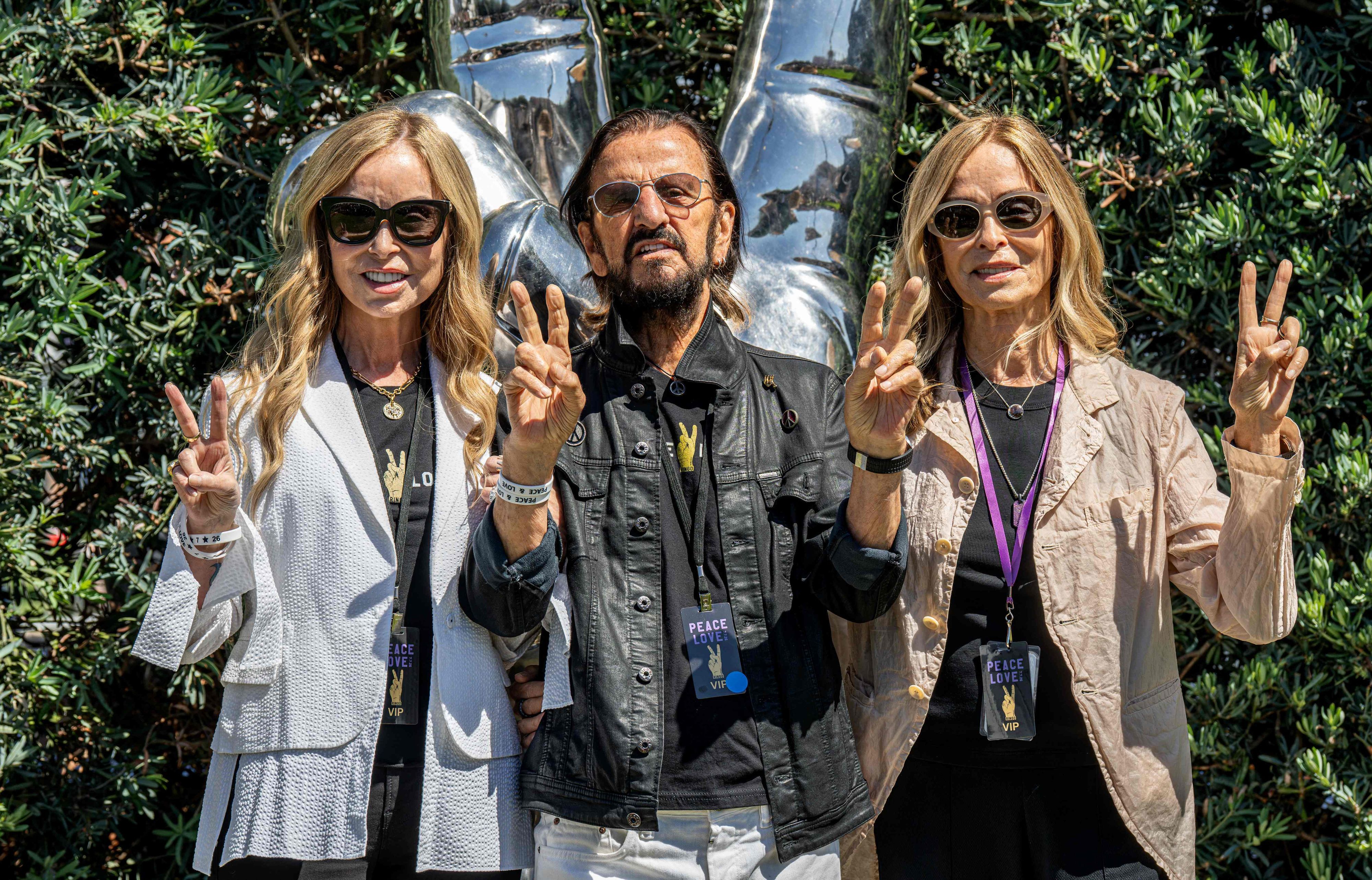 Der britische Musiker Ringo Starr (M.) posiert gemeinsam mit seiner Ehefrau Barbara Bach (l.) und deren Schwester Marjorie Bach vor der von ihm entworfenen Edelstahl-Skulptur „Peace and Love“ im Beverly Gardens Park in Beverly Hills.