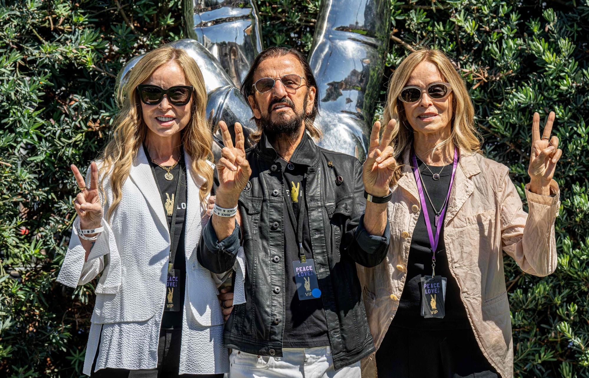 Der britische Musiker Ringo Starr (M.) posiert gemeinsam mit seiner Ehefrau Barbara Bach (l.) und deren Schwester Marjorie Bach vor der von ihm entworfenen Edelstahl-Skulptur „Peace and Love“ im Beverly Gardens Park in Beverly Hills.