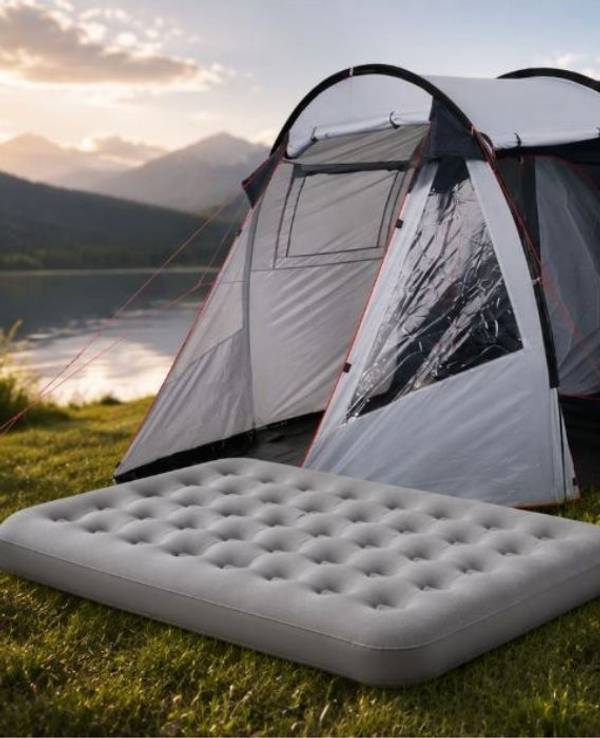 Camping Produkte wie Zelt, Luftbett, Schlafsack in einer grünen Landschaft am See und neben einem Wald.