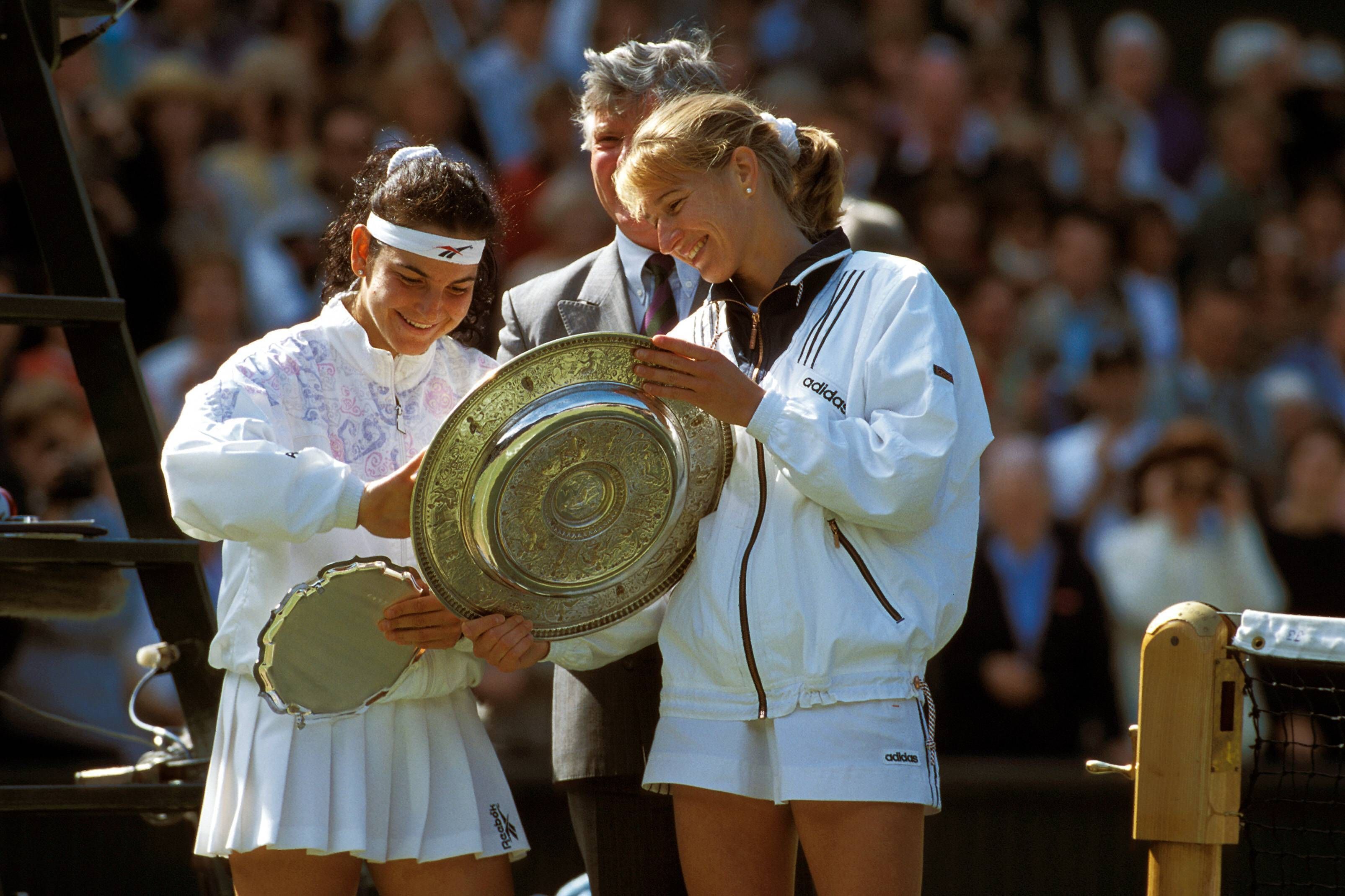 Steffi Graf und Arantxa Sánchez Vicario begutachten lächelnd ihre Trophäen nach dem Wimbledon-Finale.