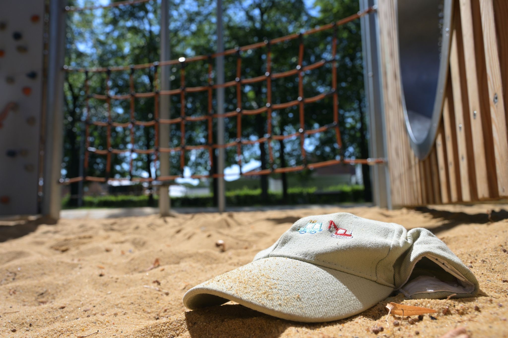 Im Sand eines Spielplatzes liegt eine Mütze.
