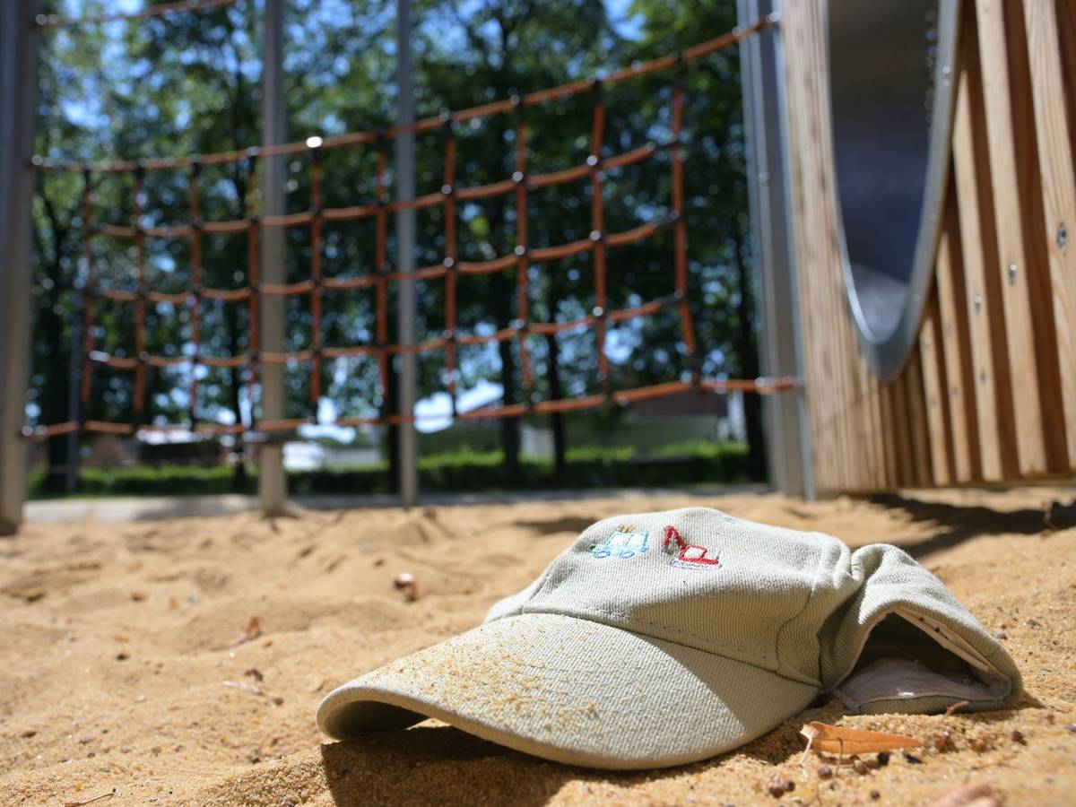 Im Sand eines Spielplatzes liegt eine Mütze.