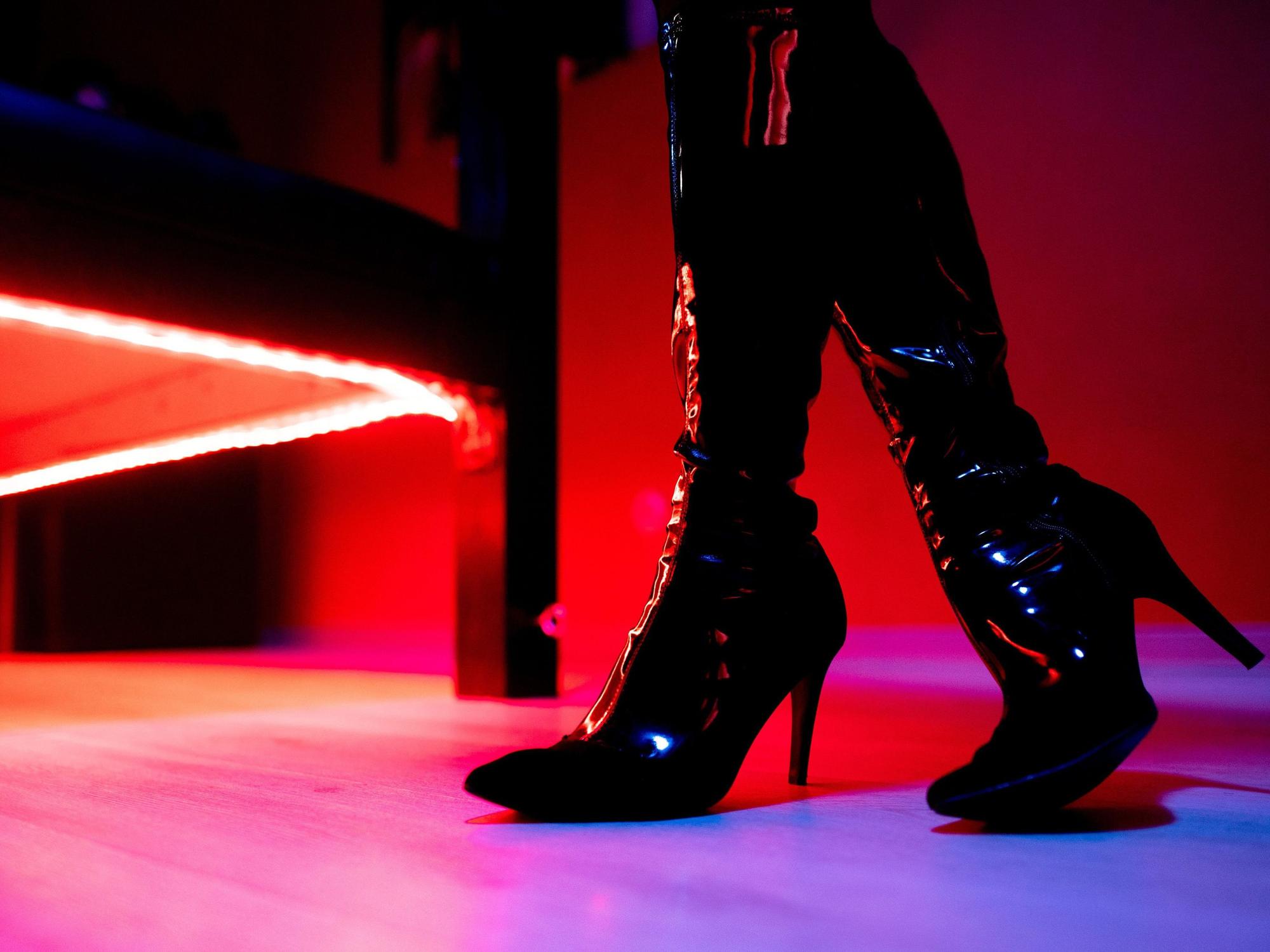 Eine Prostituierte steht vor der roten Beleuchtung unter einem Bett in einem Studio. (Symbolfoto)