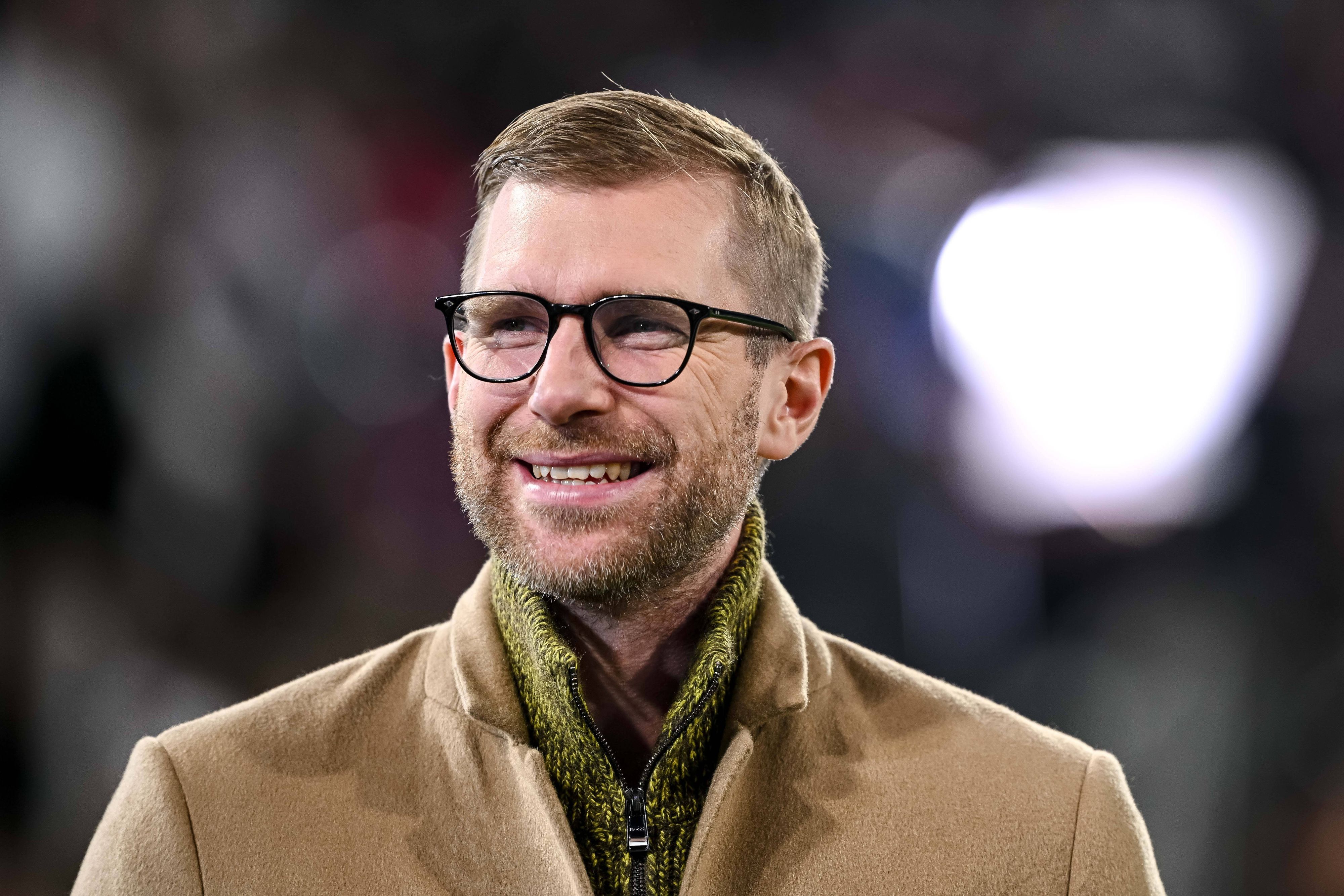 Per Mertesacker steht im Stadion und hat gute Laune.