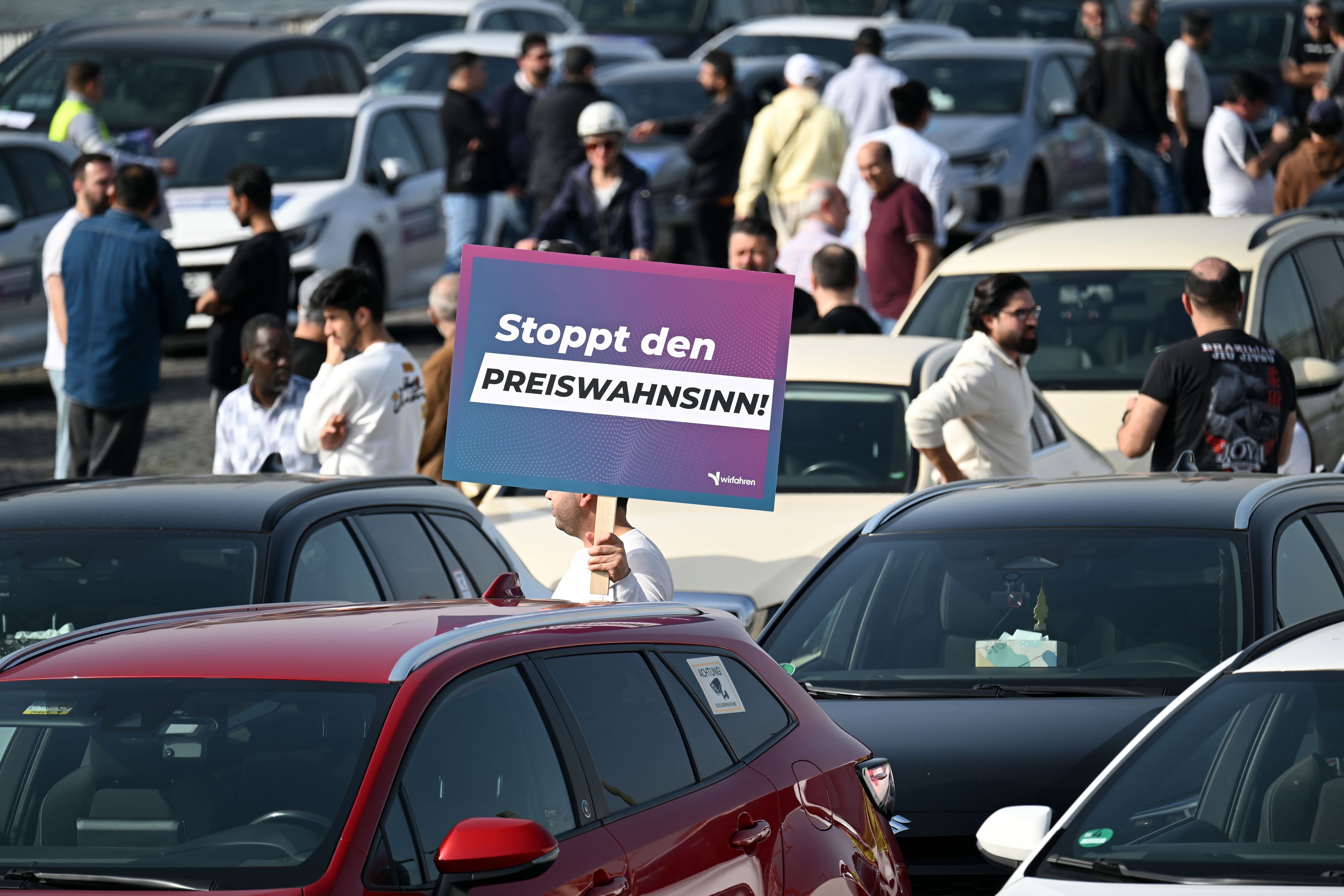 Teilnehmer einer Demonstration halten Schilder mit der Aufschrift „Stoppt das Preisdiktat“ in den Händen.