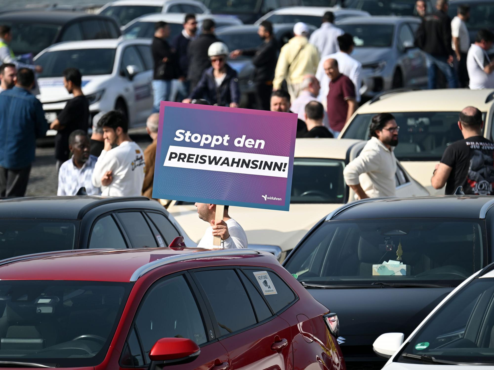 Teilnehmer einer Demonstration halten Schilder mit der Aufschrift „Stoppt das Preisdiktat“ in den Händen.