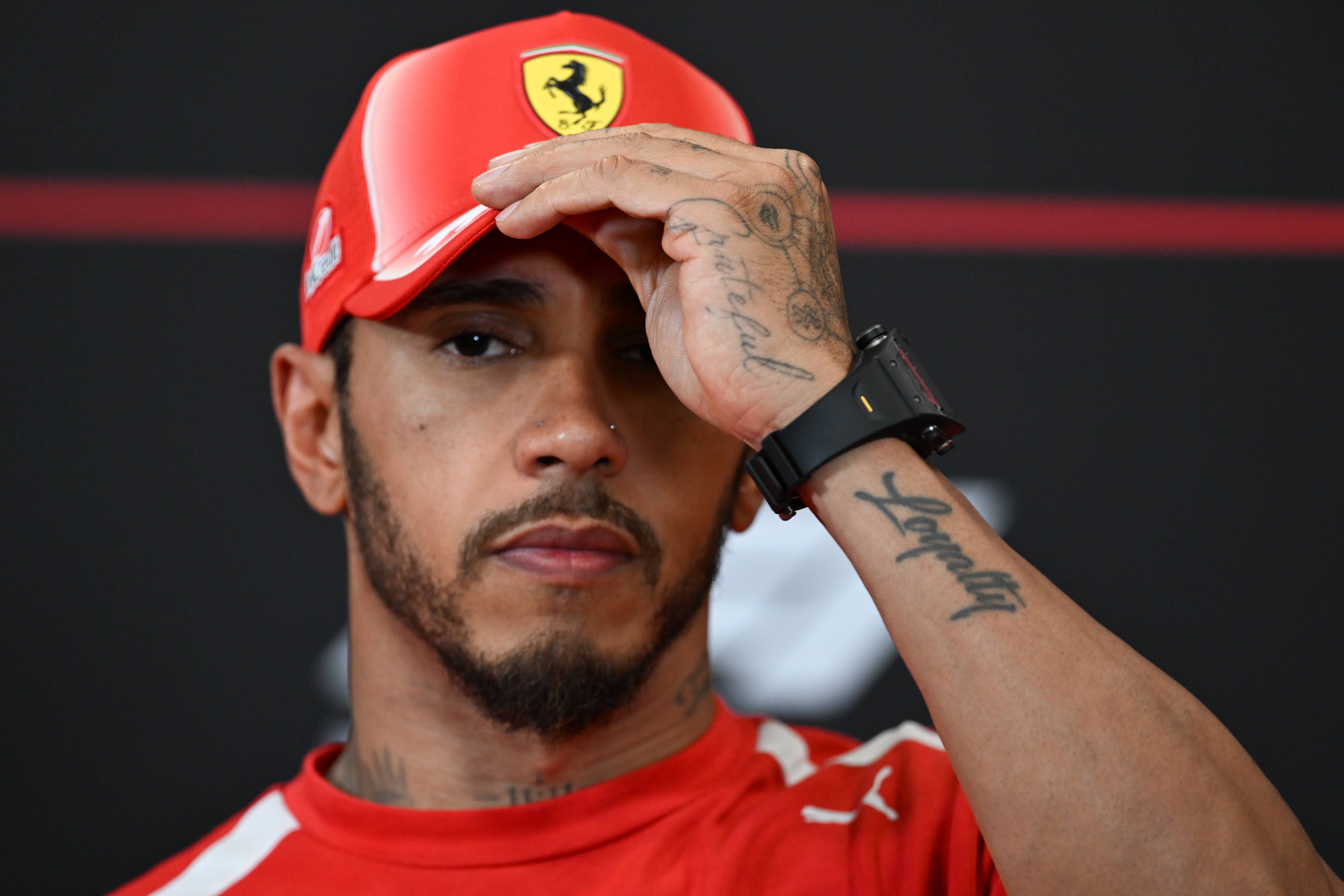 Lewis Hamilton fasst sich an die Ferrari-Kappe.