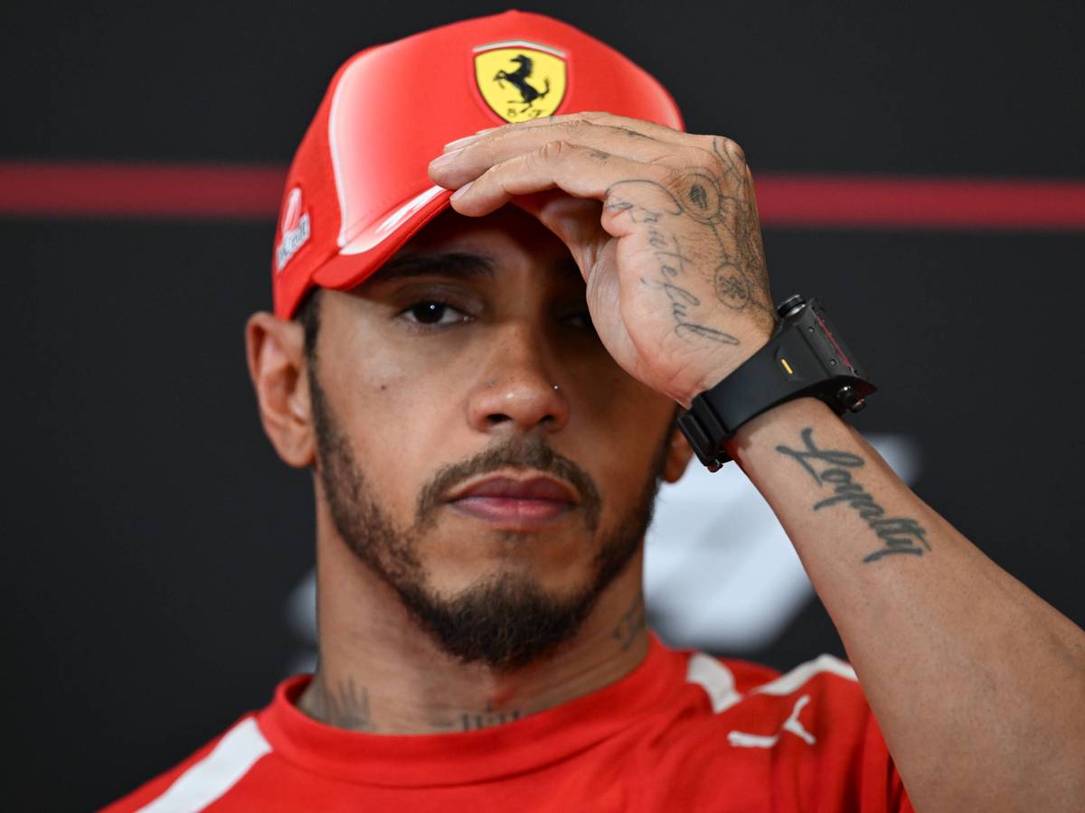 Lewis Hamilton fasst sich an die Ferrari-Kappe.