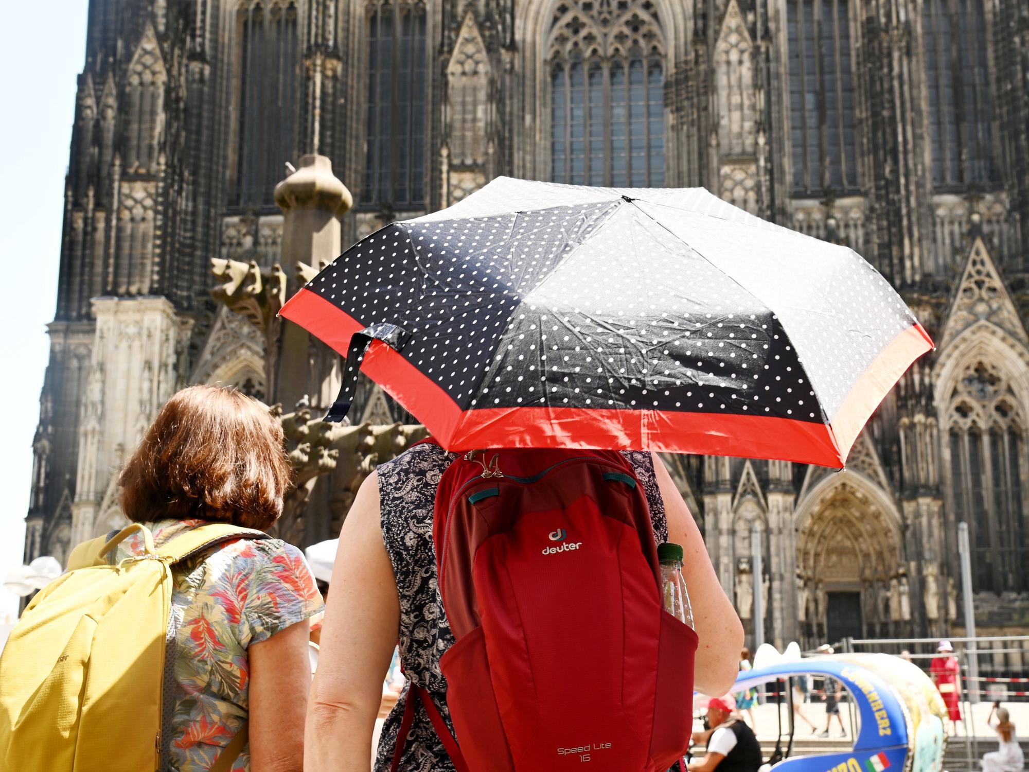 Für Köln und ganz NRW werden erneut Temperaturen jenseits der 30-Grad-Marke vorhergesagt. Schon im Juni schützten sich Menschen mit Schirmen gegen die Hitze.