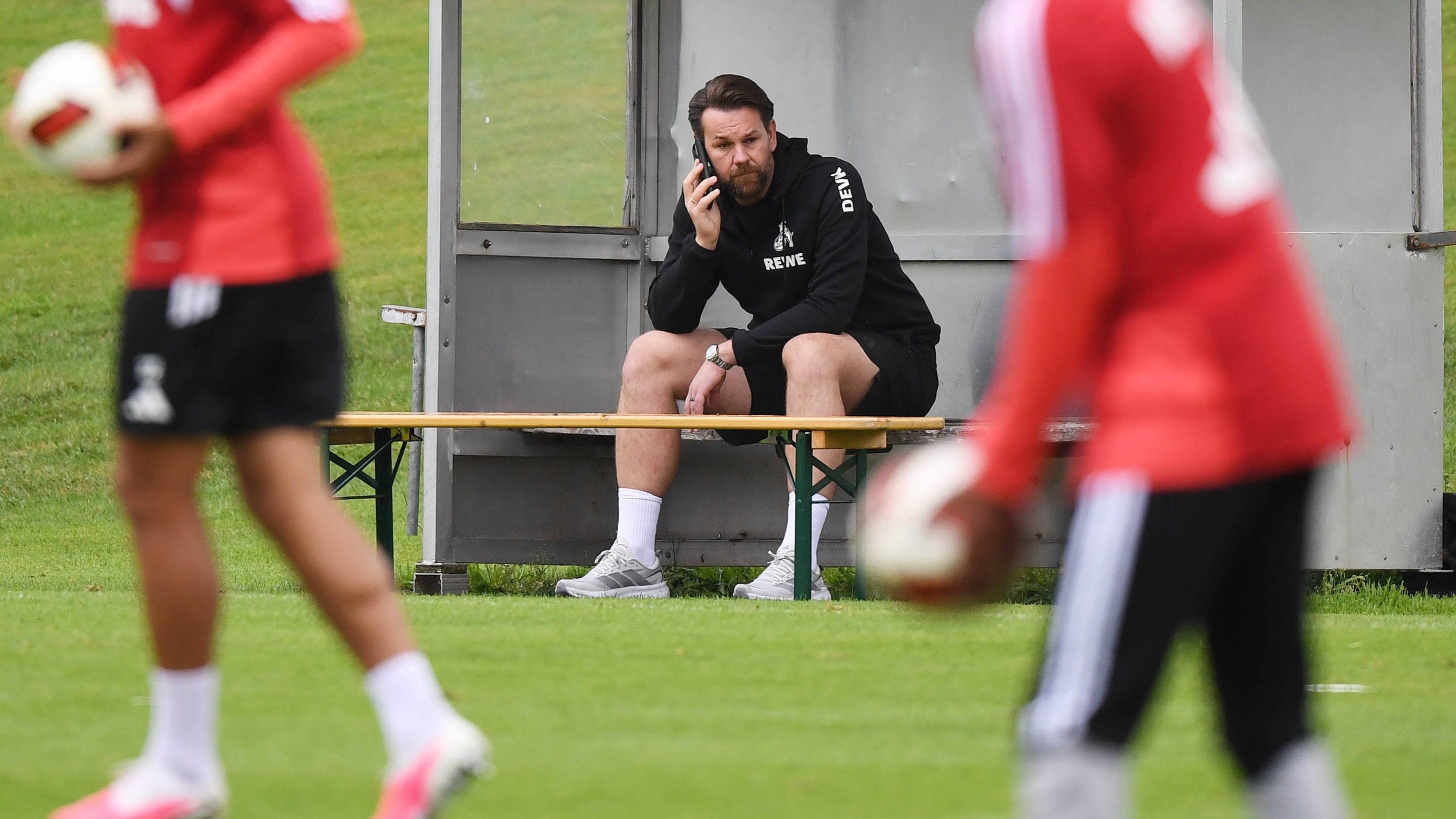 Thomas Kessler telefoniert während des Trainings beim 1. FC Köln.