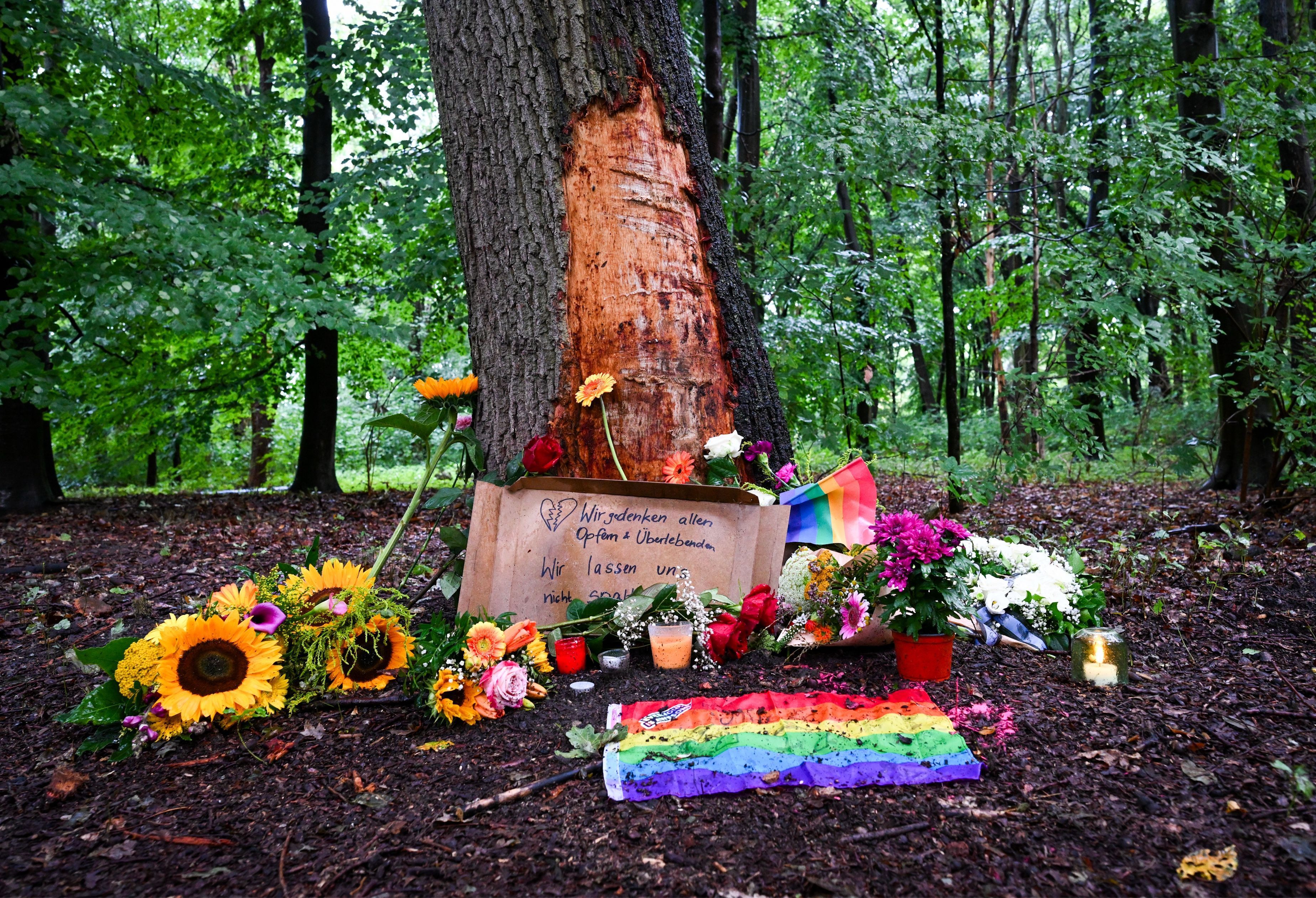 Blumen, Kerzen und die Botschaft „Wir gedenken aller Opfer und Überlebenden“ sind an einem Baum mit beschädigter Rinde zu sehen, wo ein Fahrzeug am Rande des Christopher Street Day in eine Menschenmenge gefahren war.