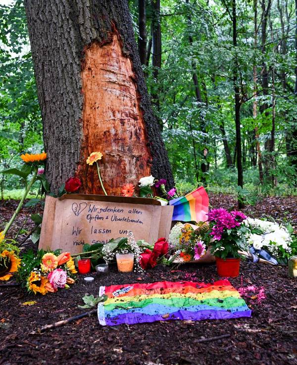 Blumen, Kerzen und die Botschaft „Wir gedenken aller Opfer und Überlebenden“ sind an einem Baum mit beschädigter Rinde zu sehen, wo ein Fahrzeug am Rande des Christopher Street Day in eine Menschenmenge gefahren war.
