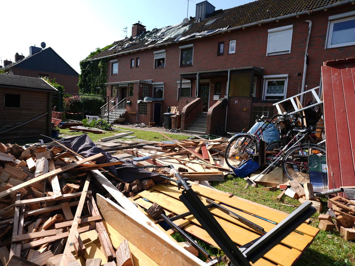 Provisorische Planen bedecken das durch ein Unwetter abgedeckte Dach eines Reihenhauses. Im Vordergrund liegen Teile einer zerstörten Gartenlaube und Dachziegel. Ein mutmaßlicher Tornado hat in und um Glückstadt in Schleswig-Holstein eine Schneise der Verwüstung geschlagen und nach ersten Schätzungen Schäden in sechs- bis siebenstelliger Höhe verursacht.