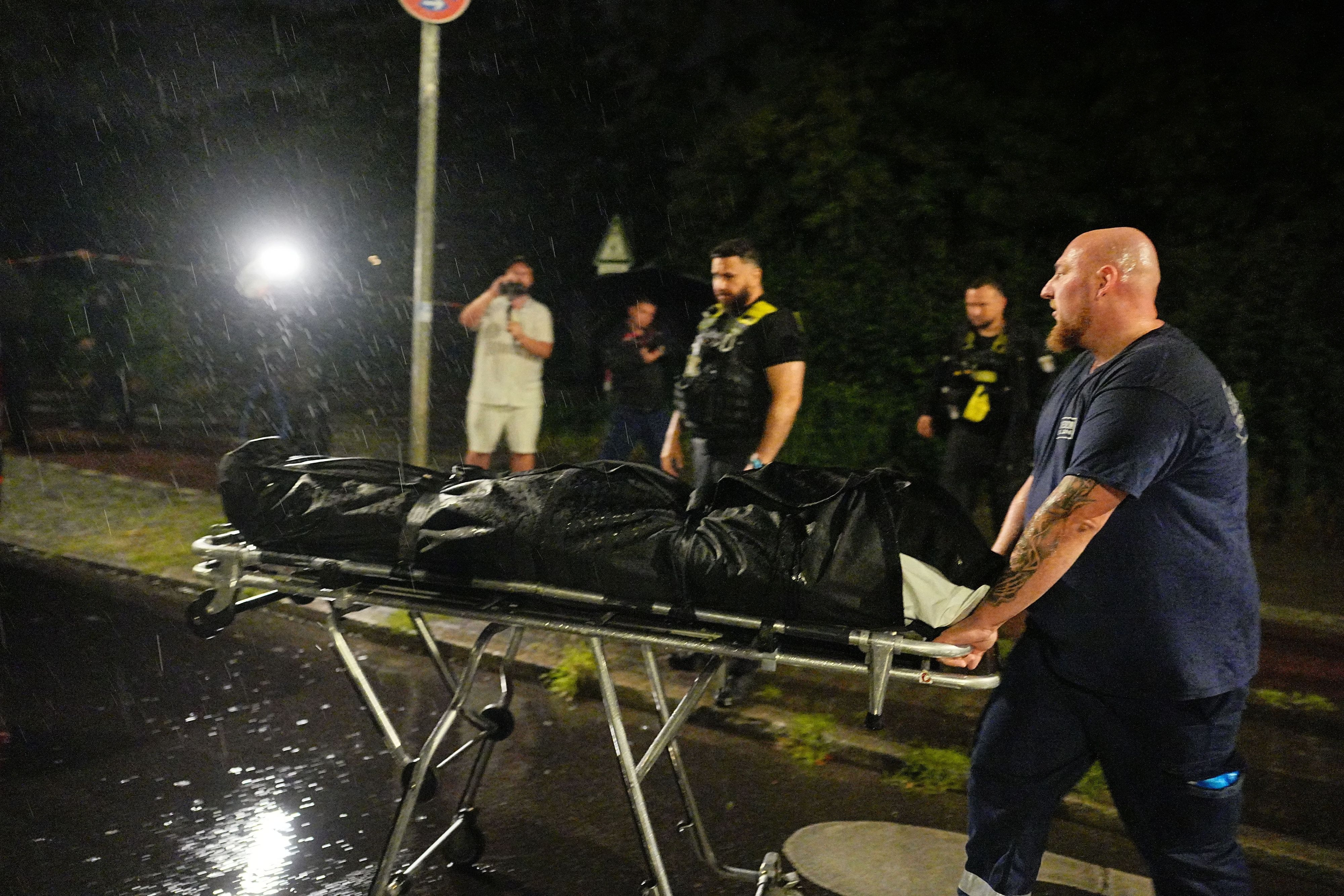 Ein Mitarbeiter der Gerichtsmediziner bringt die Leiche des mutmaßlichen Täters, der nach Polizeischüssen gestorben ist, zu einem Fahrzeug.