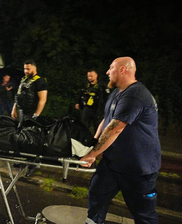 Ein Mitarbeiter der Gerichtsmediziner bringt die Leiche des mutmaßlichen Täters, der nach Polizeischüssen gestorben ist, zu einem Fahrzeug.