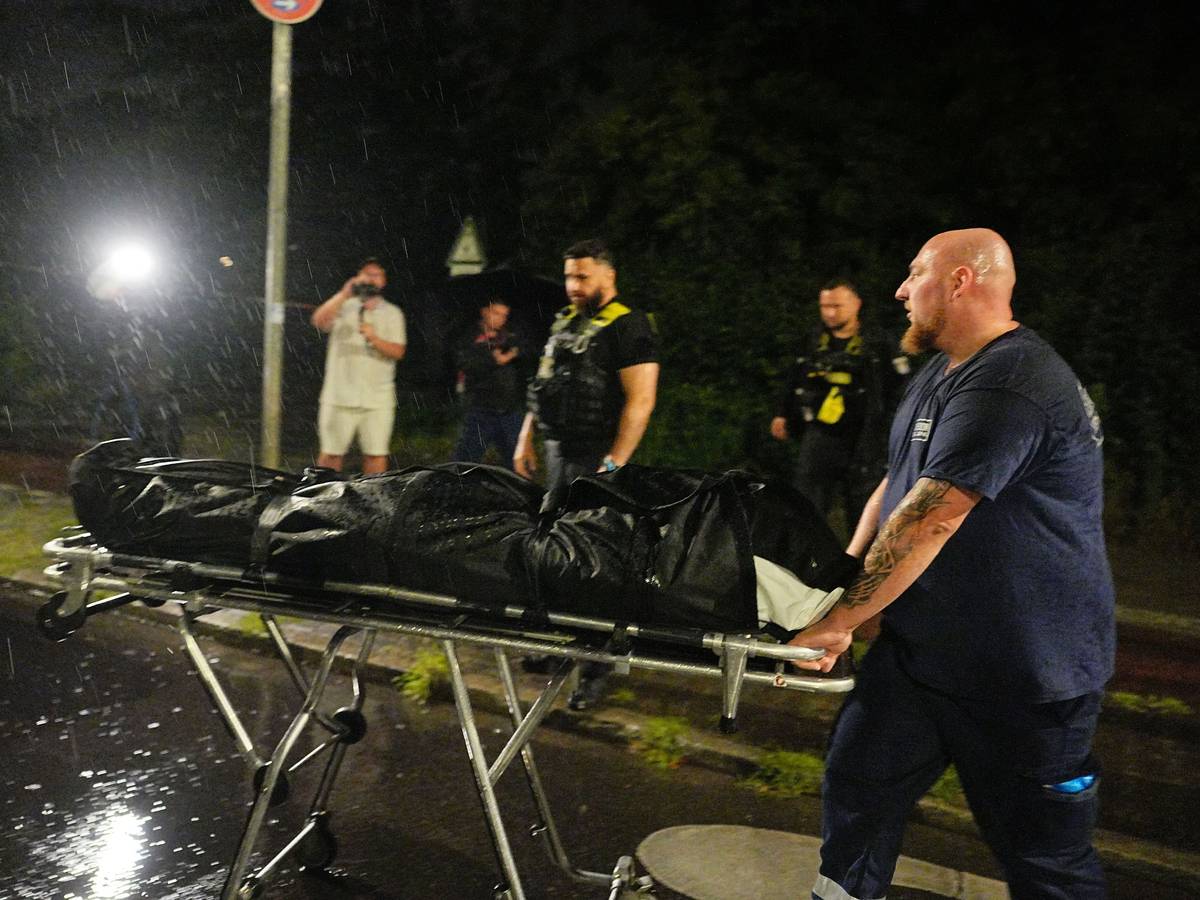 Ein Mitarbeiter der Gerichtsmediziner bringt die Leiche des mutmaßlichen Täters, der nach Polizeischüssen gestorben ist, zu einem Fahrzeug.