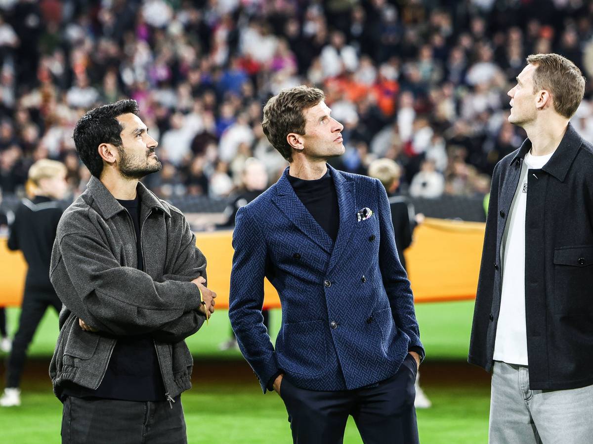 Ilkay Gündogan, Thomas Müller und Manuel Neuer stehen vor dem Spiel auf dem Platz und schauen nach oben.