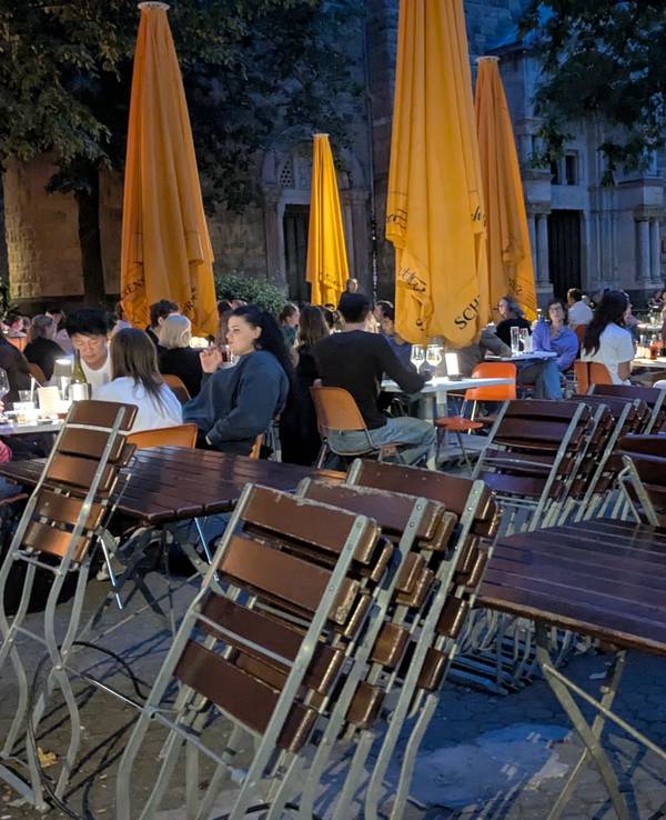 Gäste sitzen in einem Biergarten am Brüsseler Platz.