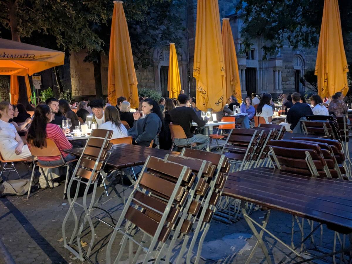 Gäste sitzen in einem Biergarten am Brüsseler Platz.