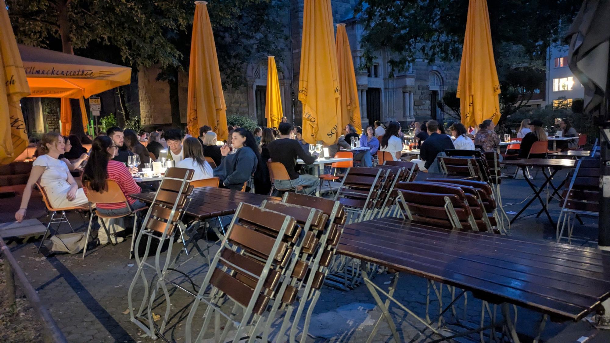 Gäste sitzen in einem Biergarten am Brüsseler Platz.