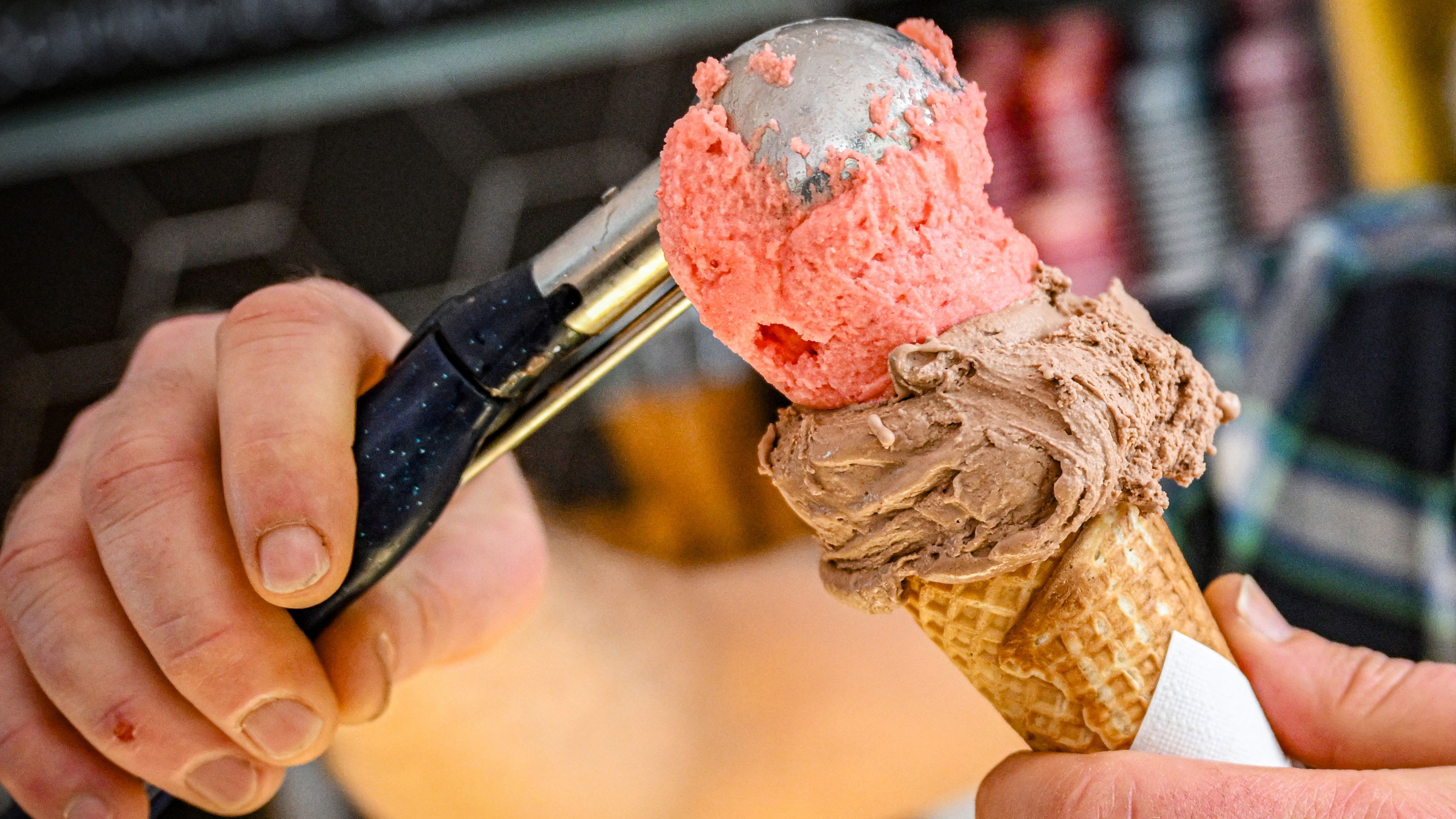 In einer Eisdiele werden zwei Eiskugeln in eine Waffel gefüllt.