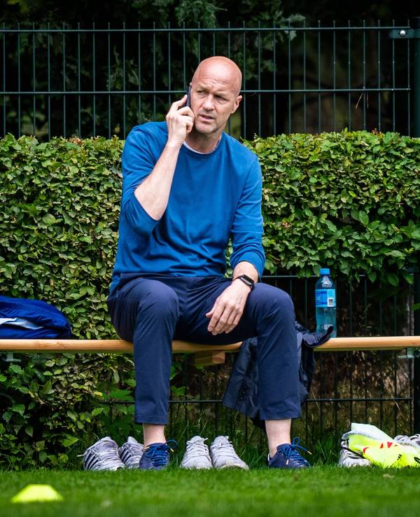 Am Rande des Trainings von Ajax Amsterdam telefoniert Jordy Cruyff auf einer Bierbank sitzend.