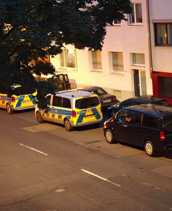 Mehrere Polizeifahrzeuge parken vor einer Häuserfront.