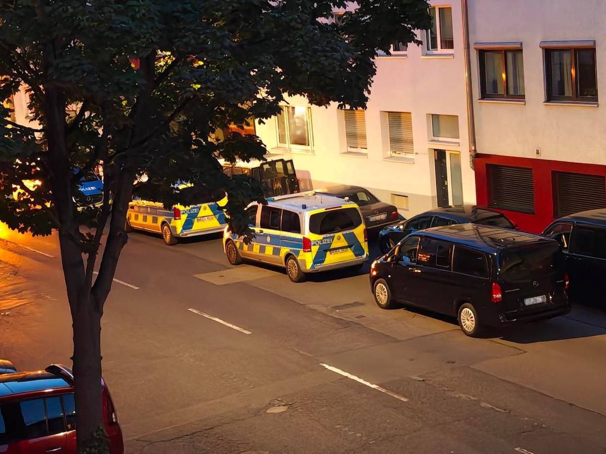 Mehrere Polizeifahrzeuge parken vor einer Häuserfront.