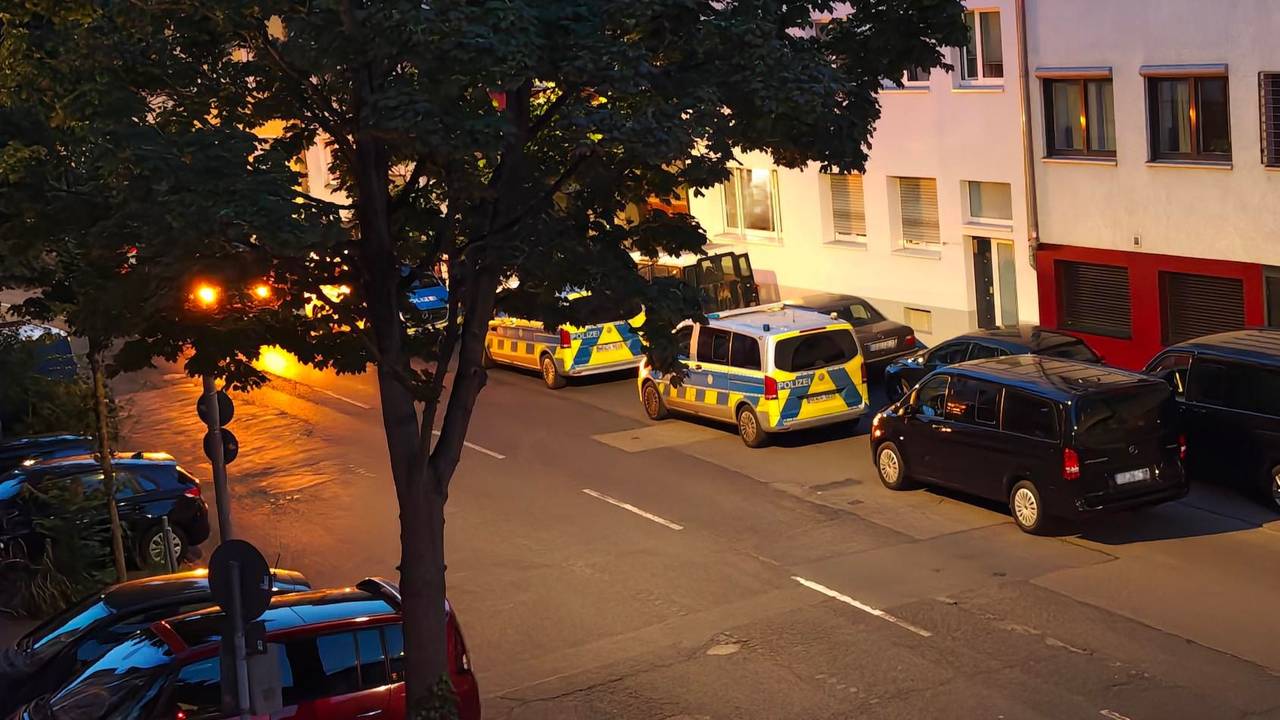 Mehrere Polizeifahrzeuge parken vor einer Häuserfront.